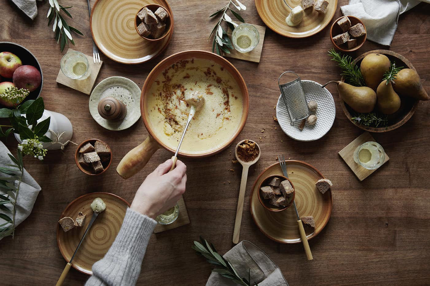 Fonduepfanne und diverse Teller und Lebensmittel auf einem Tisch