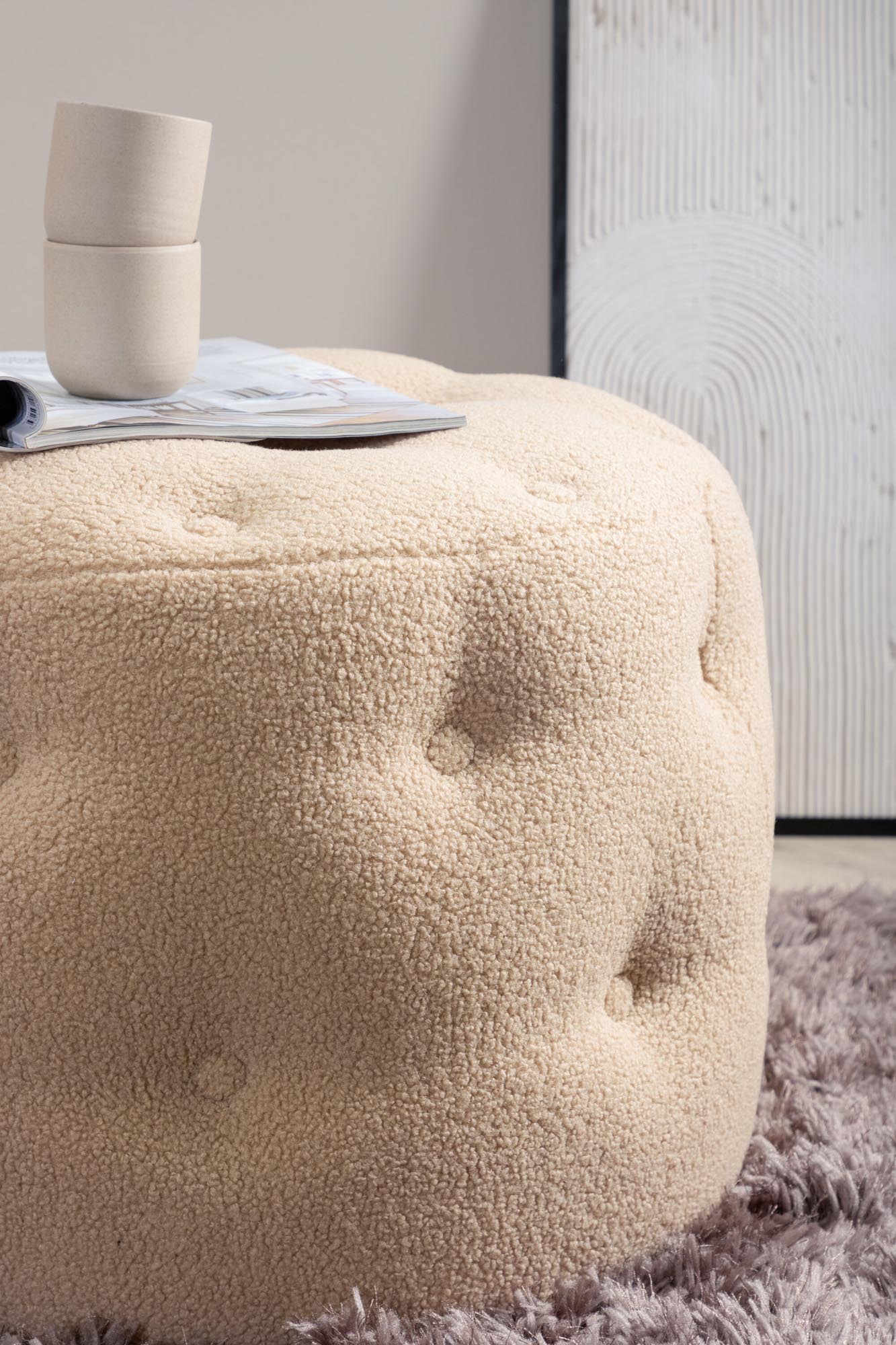 Der Benjamin Ottoman / Pouf von Venture Home vereint elegantes Design und hohen Komfort. Der zylinderförmige Pouf aus luxuriösem Teddystoff in Beige ist ein stilvolles Highlight für jedes Zuhause.
