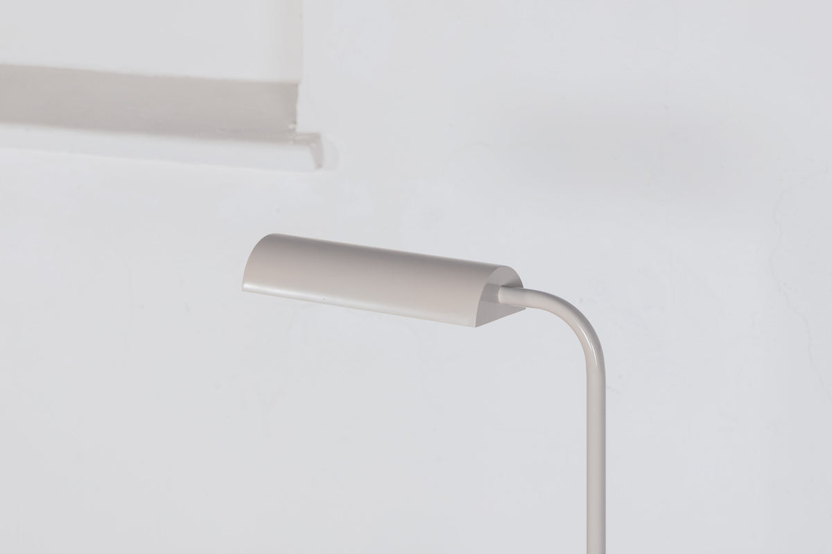 Schlanke Stehleuchte in Beige aus PVC und Stahl, schmaler Lampenschirm auf hohem Standfuss, schlichte moderne Form.