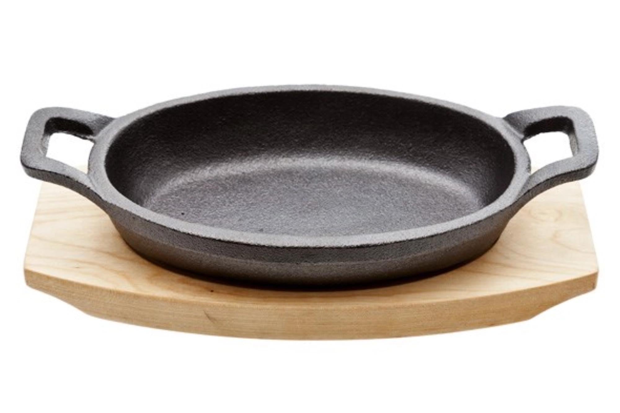 Kompakte Gusseisenpfanne (15.5x10 cm) auf stilvollem Holzbrett, ideal für kleine Portionen und gleichmässiges Garen.