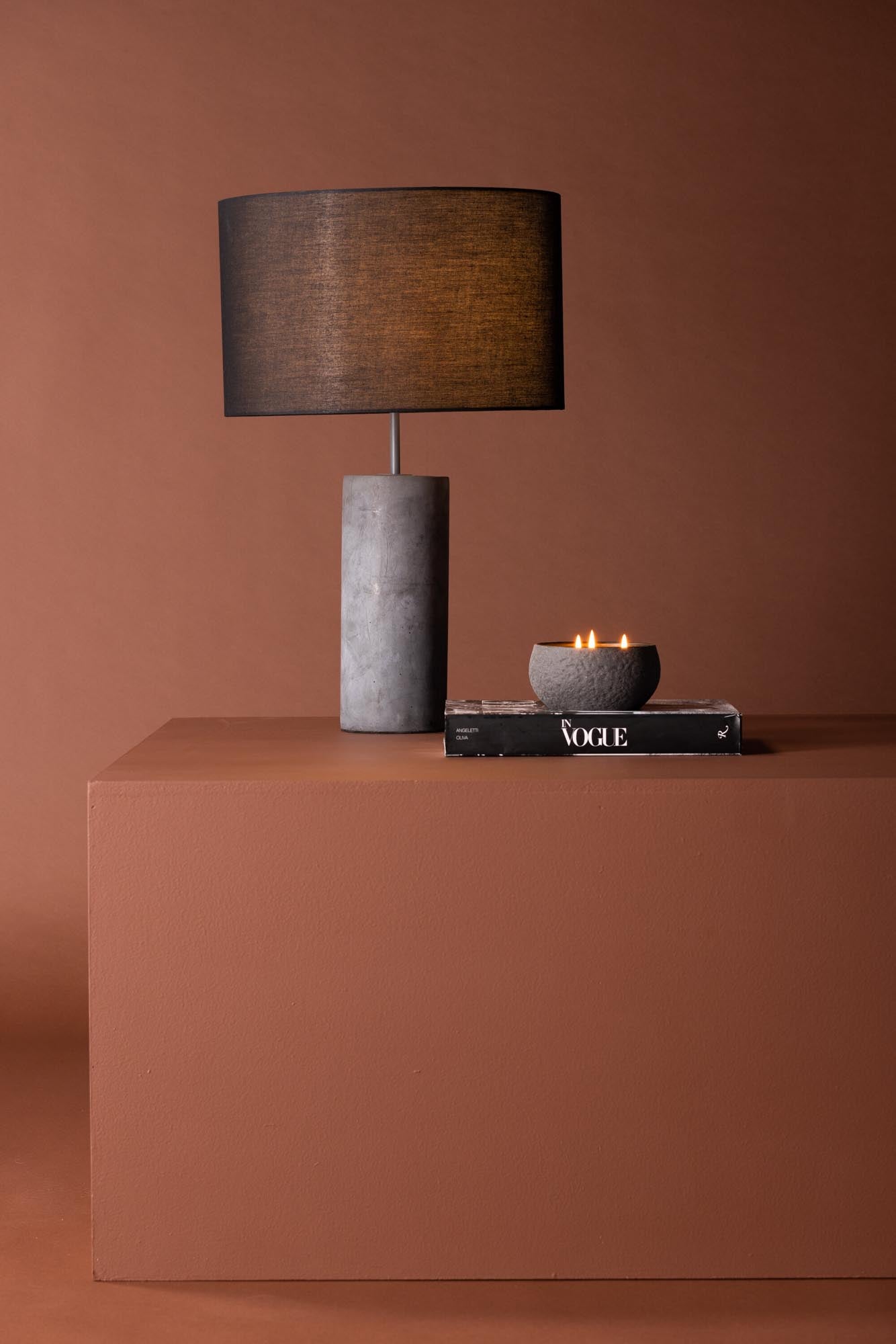 Die Nancy Tischleuchte von Venture Home vereint industriellen Charme mit modernem Design: grauer Betonfuss, schwarzer Leinenlampenschirm.