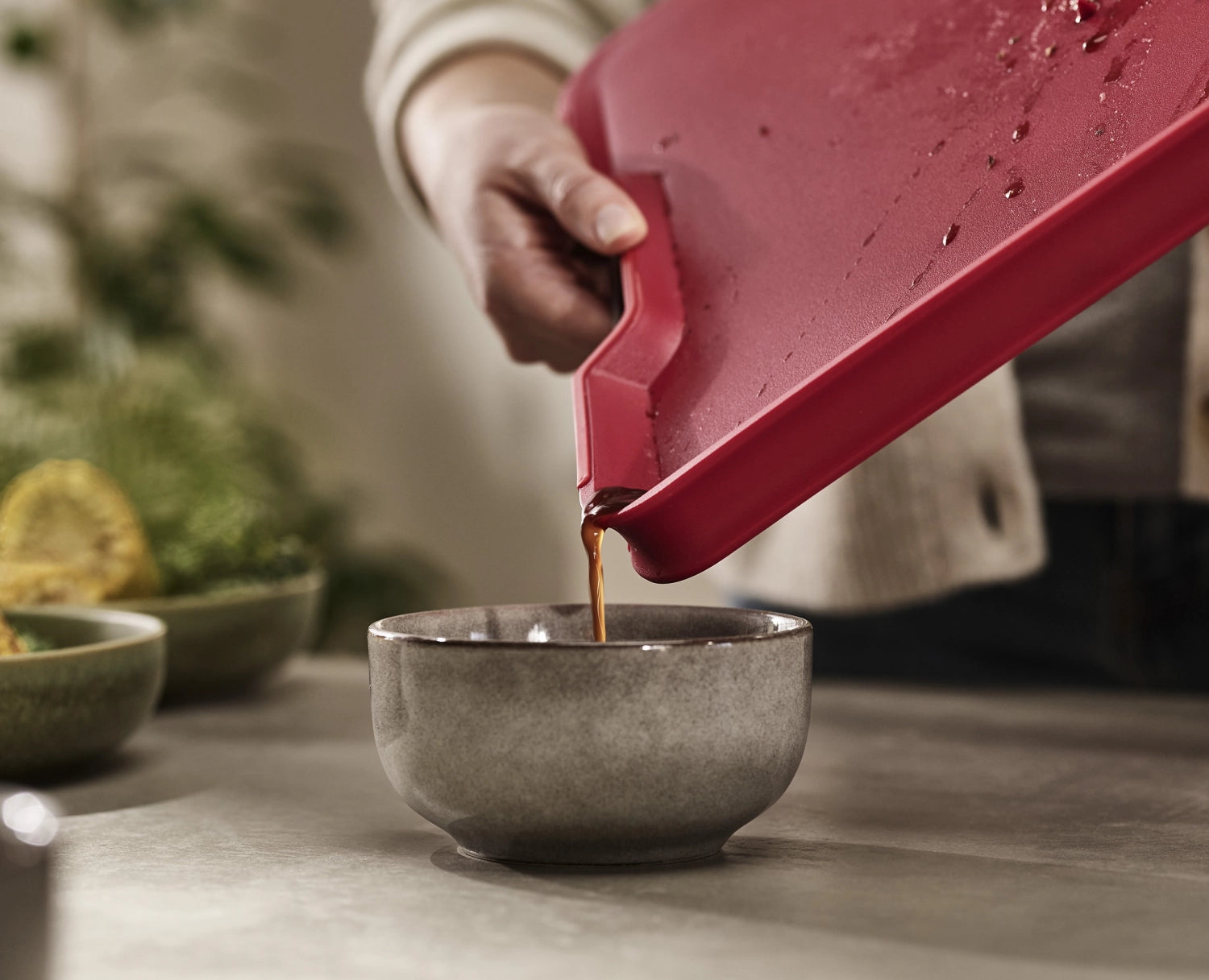 Praktisches rotes Schneidebrett Cut&Carve Plus von Joseph Joseph, perfekt für die Zubereitung und Präsentation von Speisen, mit innovativen Rillen.