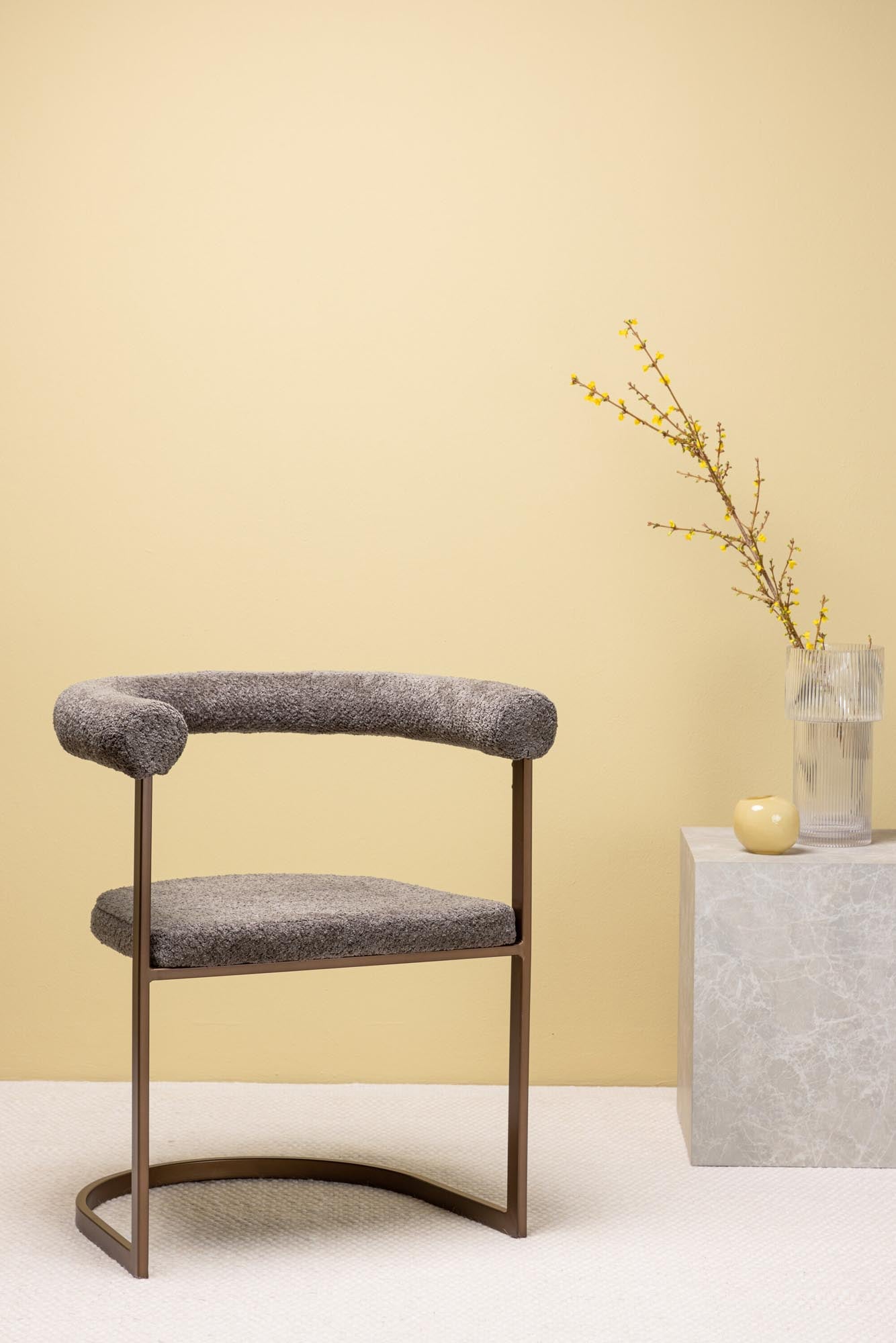 Eleganter Esszimmerstuhl mit ergonomischer Schale, gepolstertem Sitz aus grauem Boule-Stoff und stabiler Rahmenkonstruktion aus braunem Stahl.