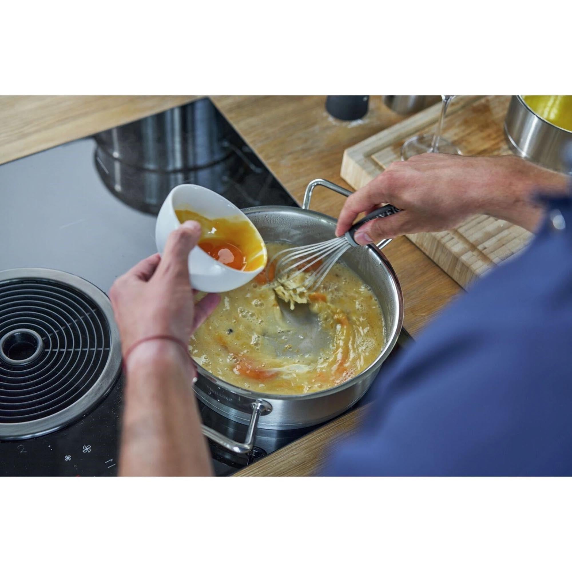 Entdecken Sie die ZWILLING Pro Servierpfanne, 24 cm: Robuste Edelstahlkonstruktion, ideal für gleichmäßiges Garen und müheloses Servieren.