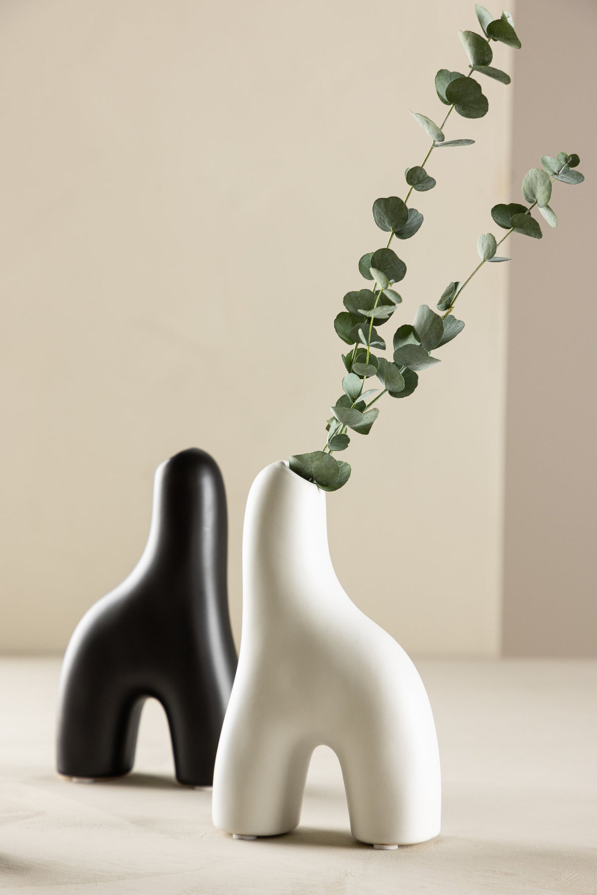 Weisse Vase Aya von Venture Home aus Steinzeug mit schlanker, eigenwilliger Form, freigestellt fotografiert.