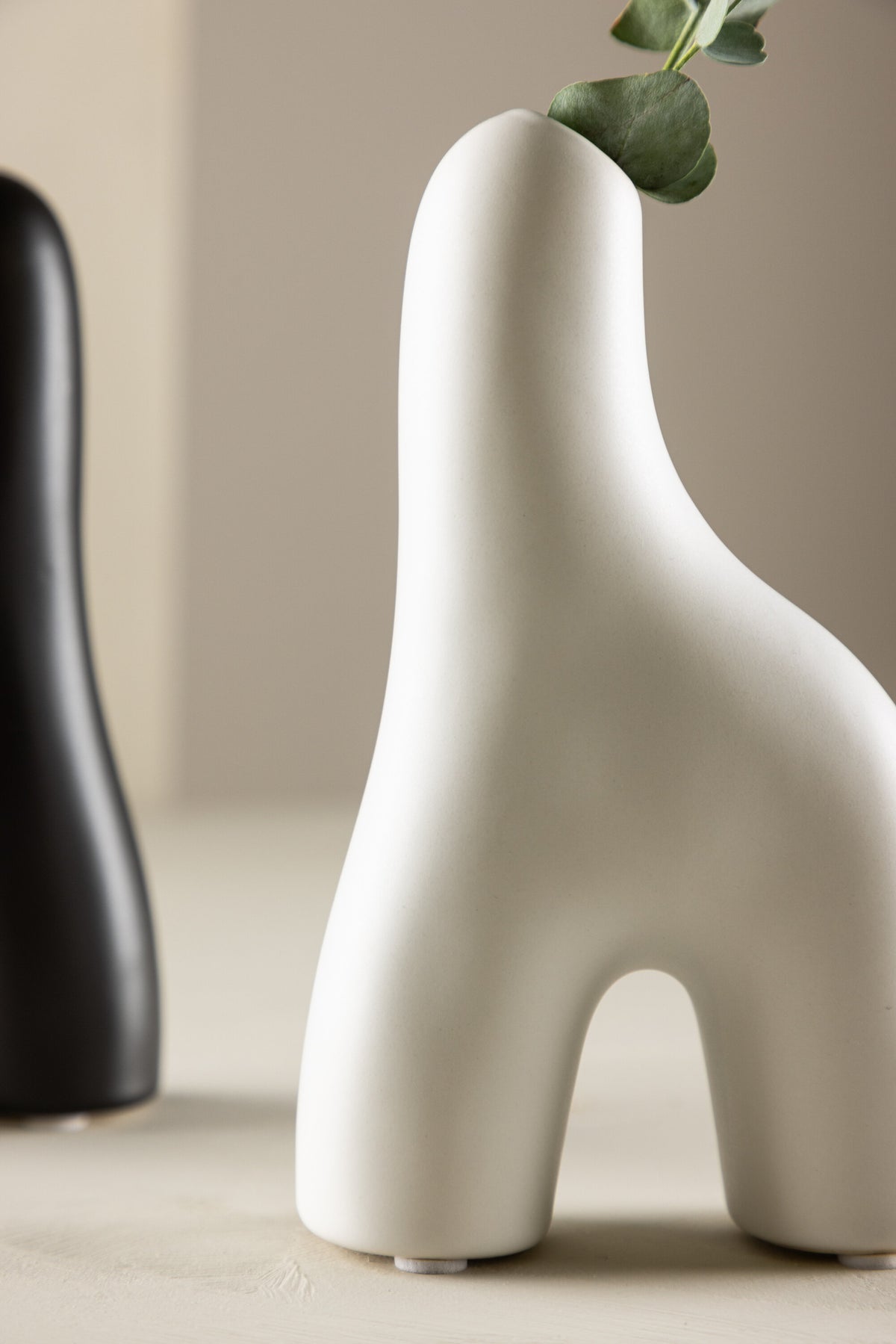 Weisse Vase Aya von Venture Home aus Steinzeug mit schlanker, eigenwilliger Form, freigestellt fotografiert.