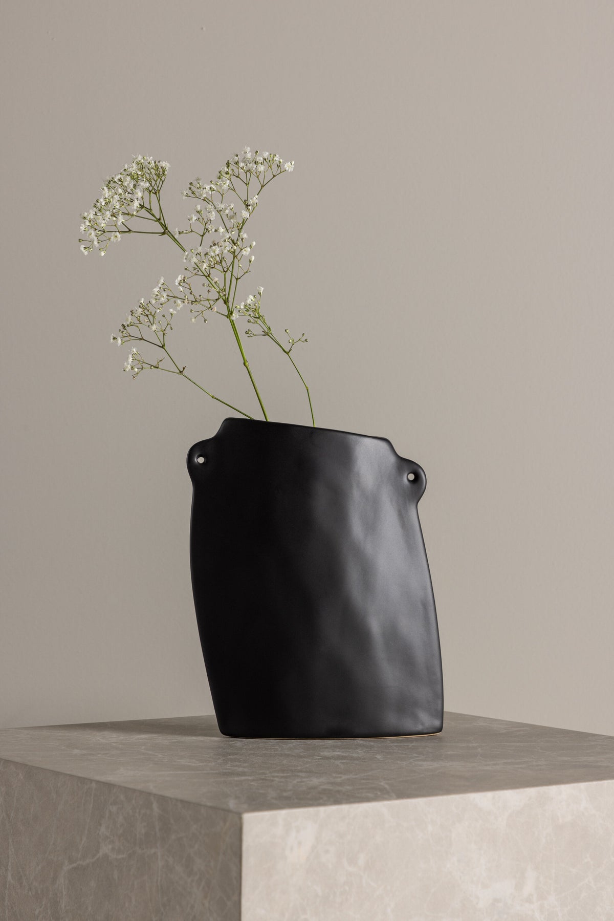 Schwarze Hie Vase von Venture Home aus Steinzeug mit schmaler Öffnung und zwei seitlichen Griffen, freigestellt fotografiert.