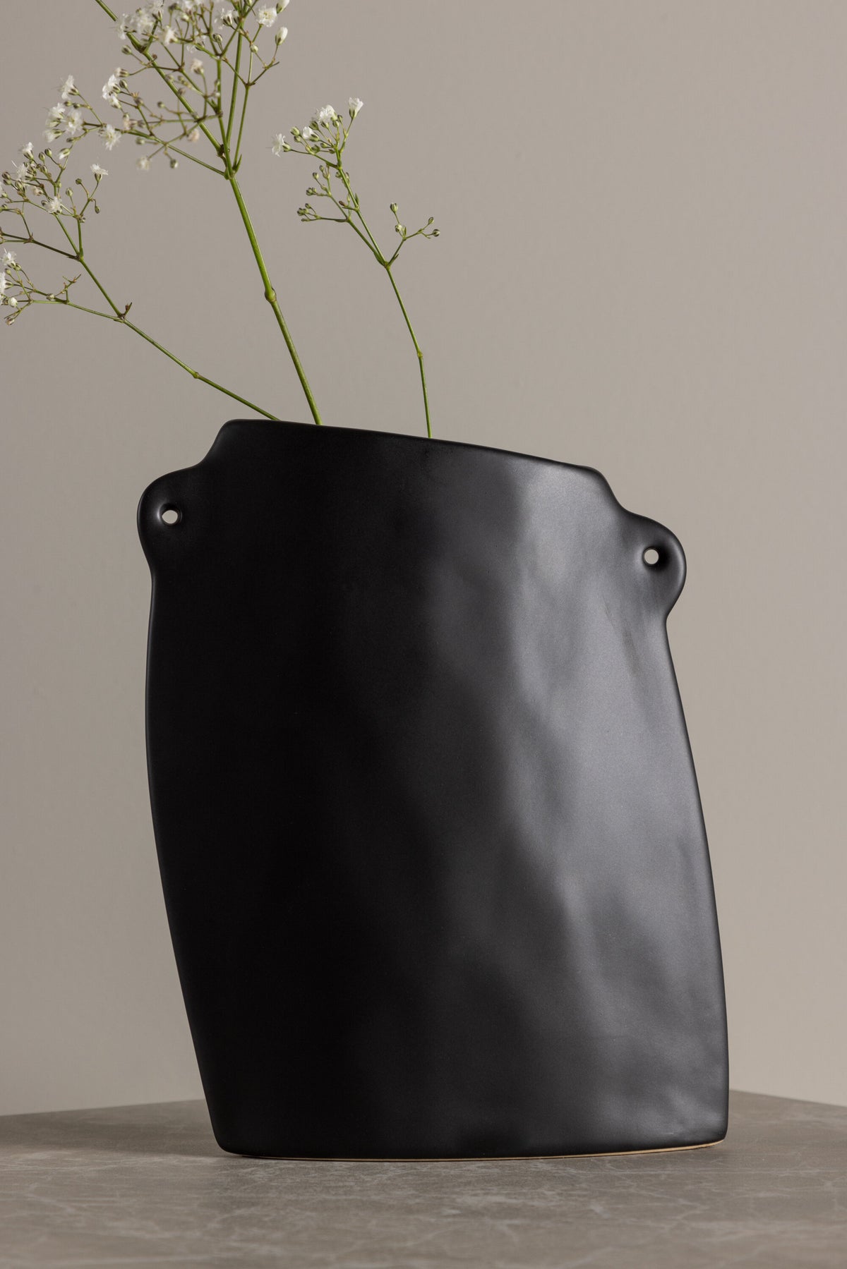 Schwarze Hie Vase von Venture Home aus Steinzeug mit schmaler Öffnung und zwei seitlichen Griffen, freigestellt fotografiert.