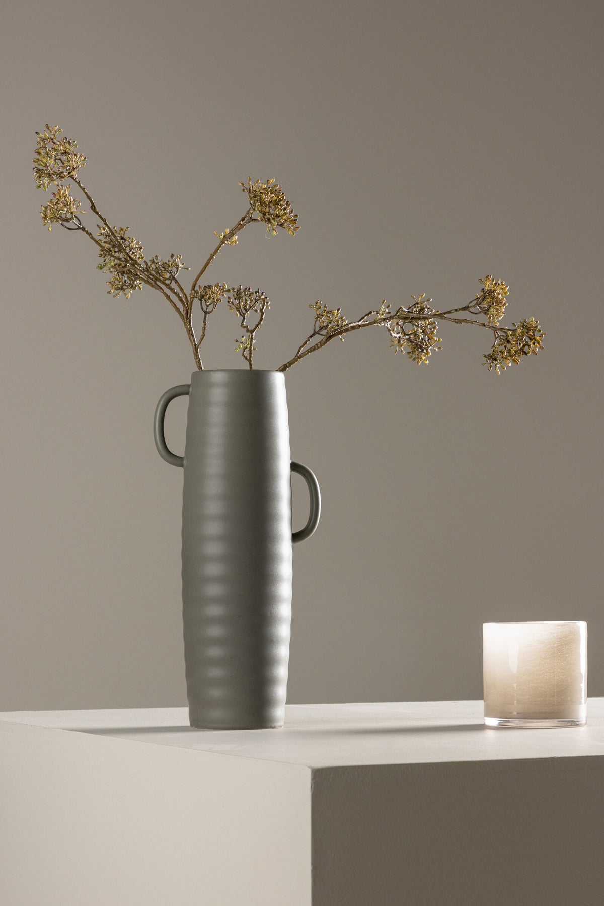 Beige Cent Vase von Venture Home aus Steinzeug mit wellenförmiger Struktur und zwei asymmetrisch angebrachten Griffen an den Seiten.