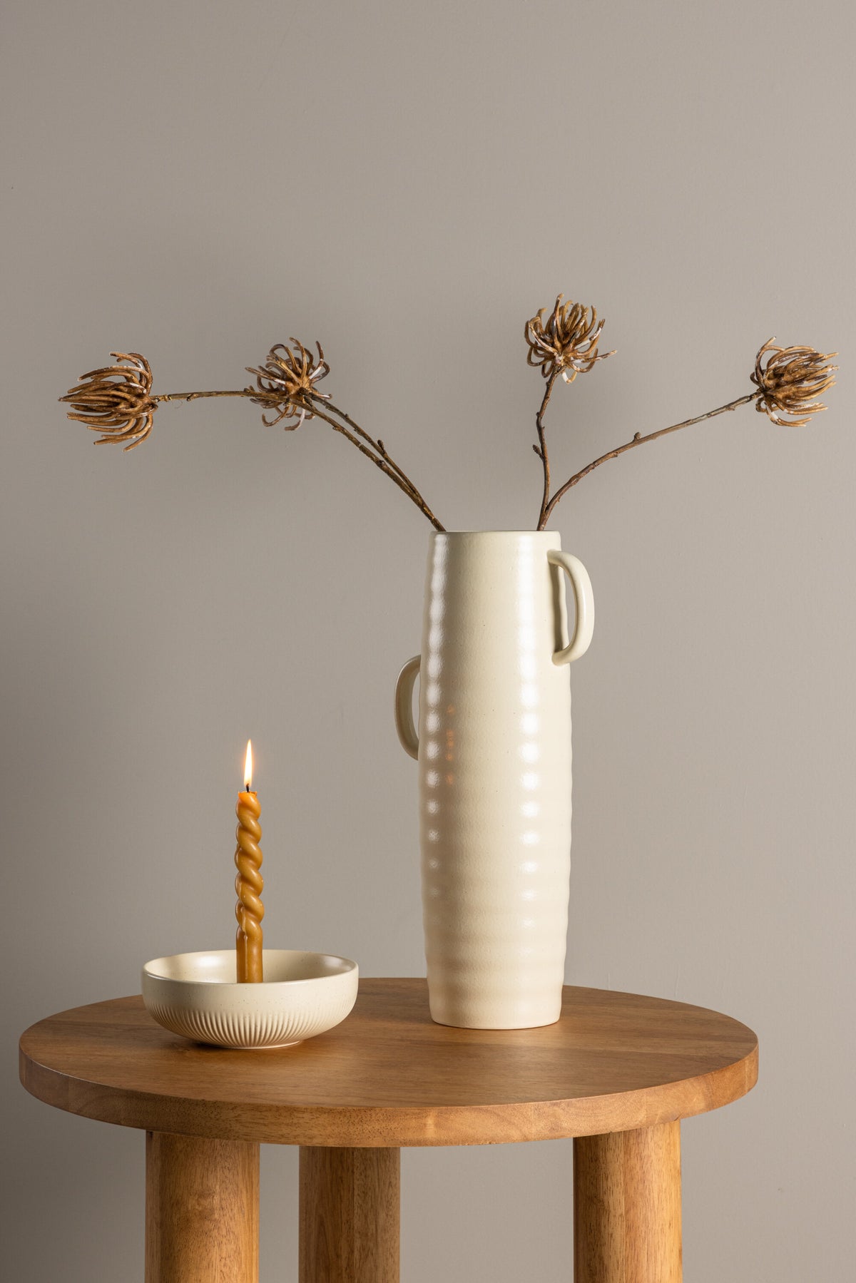 Beige Cent Vase von Venture Home aus Steinzeug mit wellenförmiger Struktur und zwei asymmetrisch angebrachten Griffen an den Seiten.