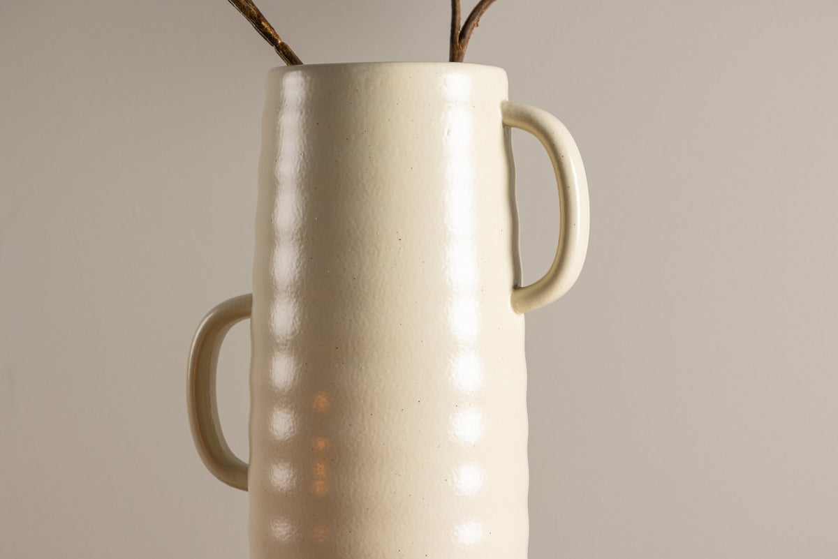Beige Cent Vase von Venture Home aus Steinzeug mit wellenförmiger Struktur und zwei asymmetrisch angebrachten Griffen an den Seiten.