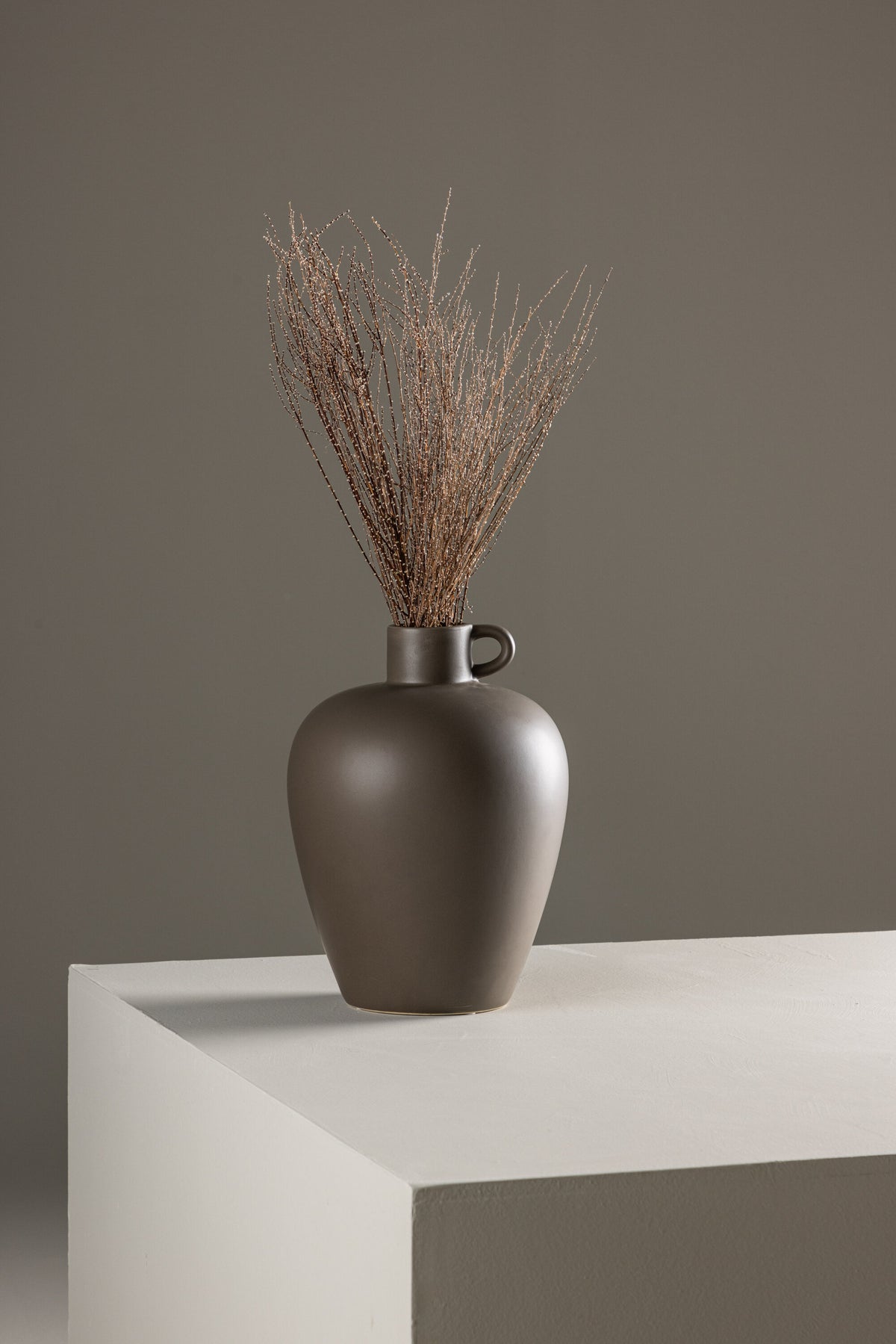 Beige Cent Vase von Venture Home aus Steinzeug mit wellenförmiger Struktur und zwei asymmetrisch angebrachten Griffen an den Seiten.