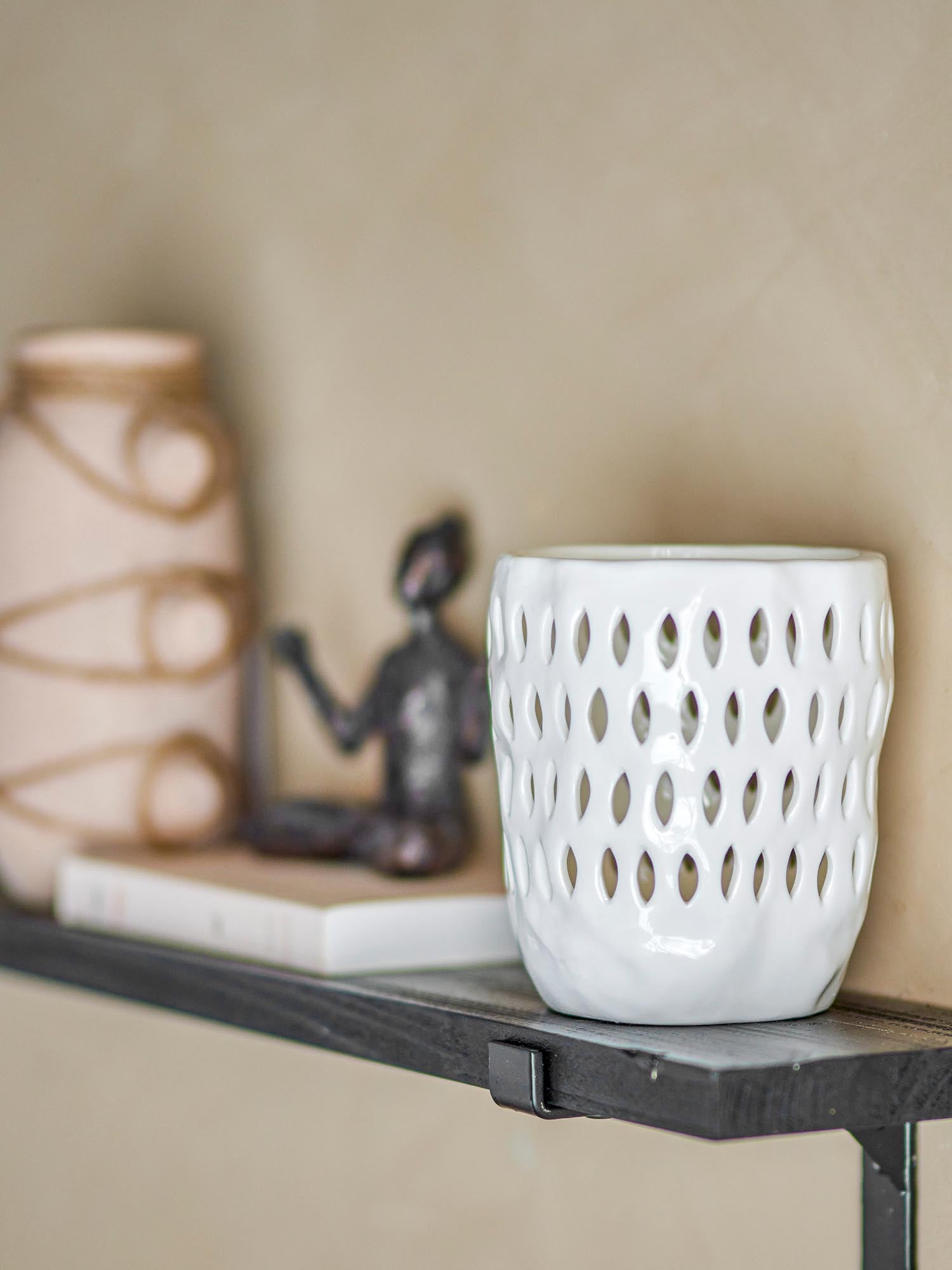 Eleganter Teelichthalter aus weissem Steingut, der mit kunstvollen Löchern ein warmes Lichtspiel erzeugt.