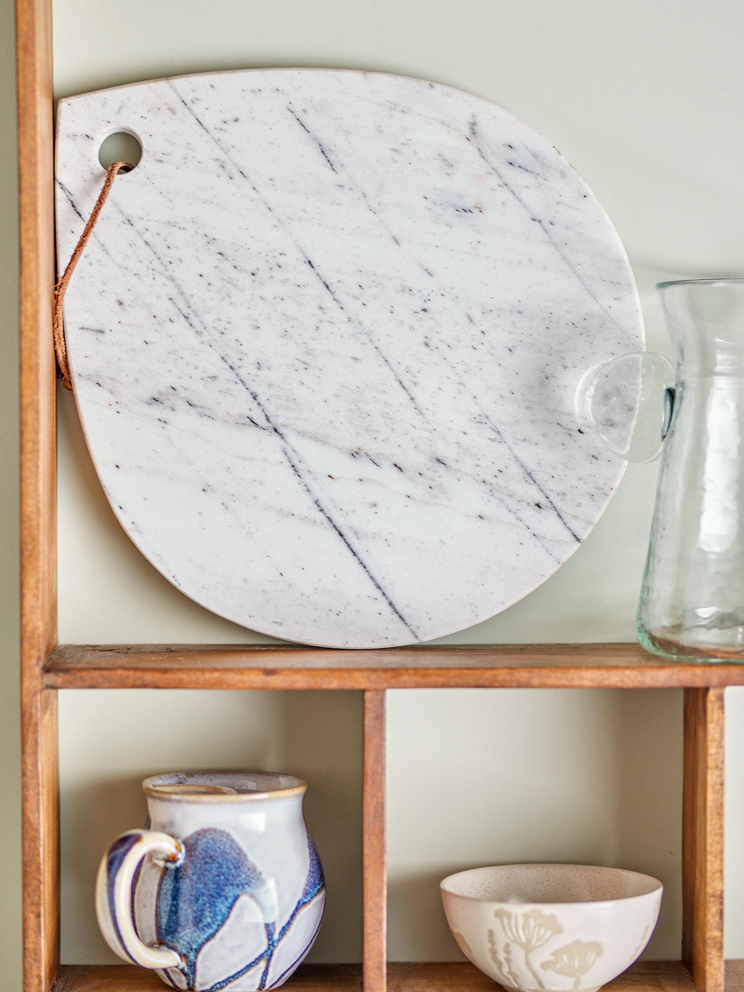 Elegantes, weisses Marmor-Schneidebrett in Tropfenform, ideal zum Schneiden und Servieren, mit einzigartiger Maserung und Aufhängeschnur.