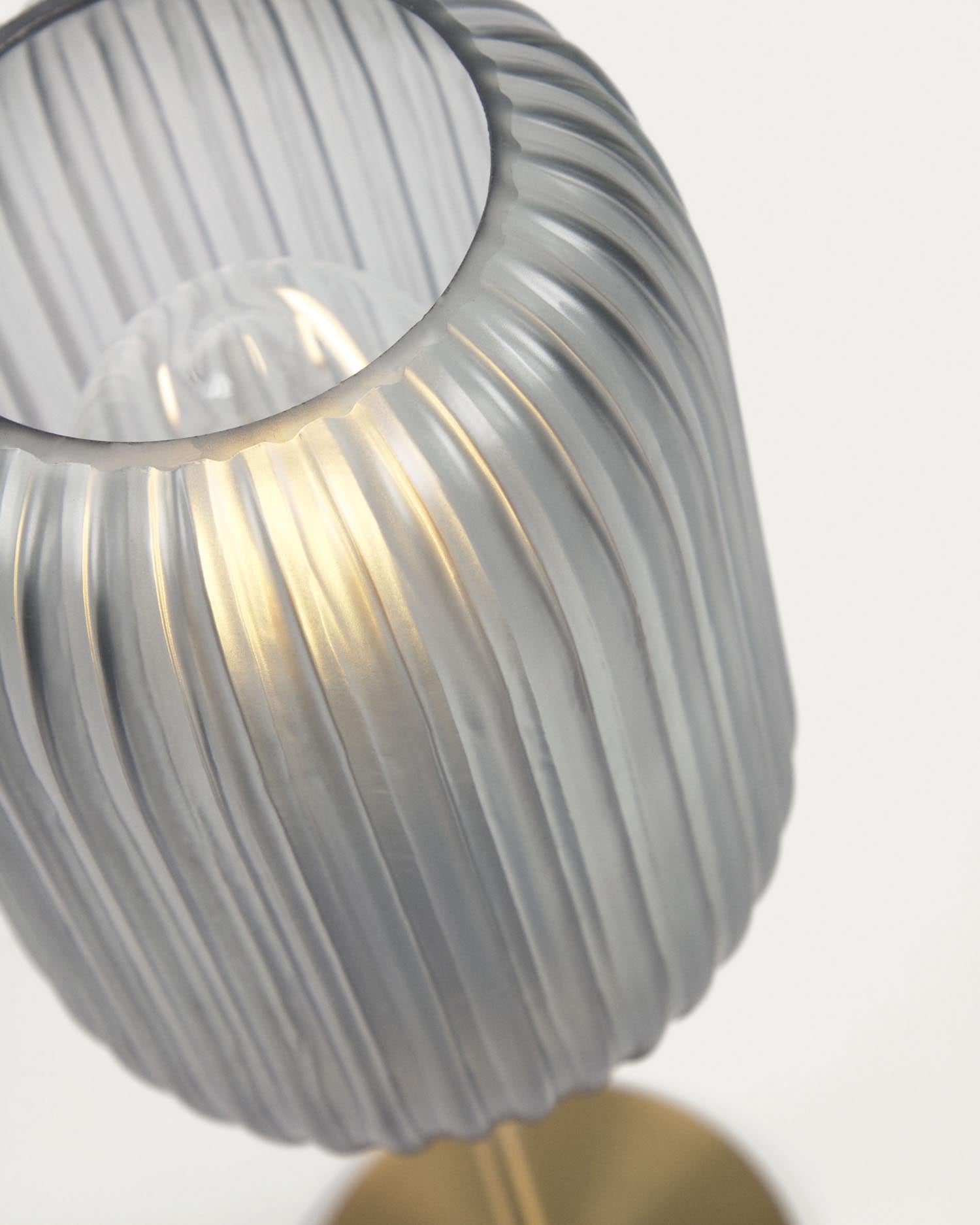 Die Hestia Tischlampe von Kave Home kombiniert hochwertiges Metall mit einem luxuriösen Messing-Finish und einem eleganten grauen Glasschirm für zeitlose Schönheit.