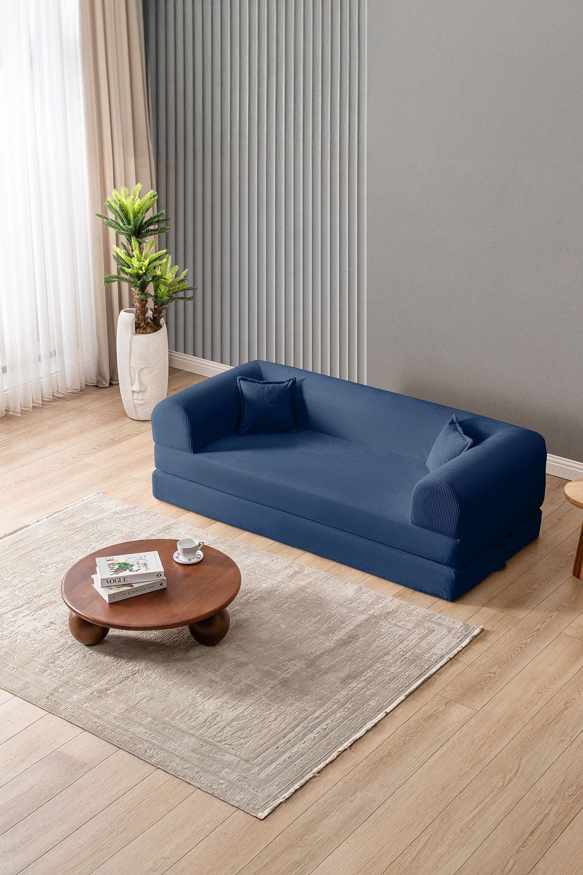 Marineblaues 3-Sitzer Schlafsofa Legom Eco von Hanah Home aus geripptem Cord-Plüschstoff mit zwei Kissen und niedrigem Rückenteil.