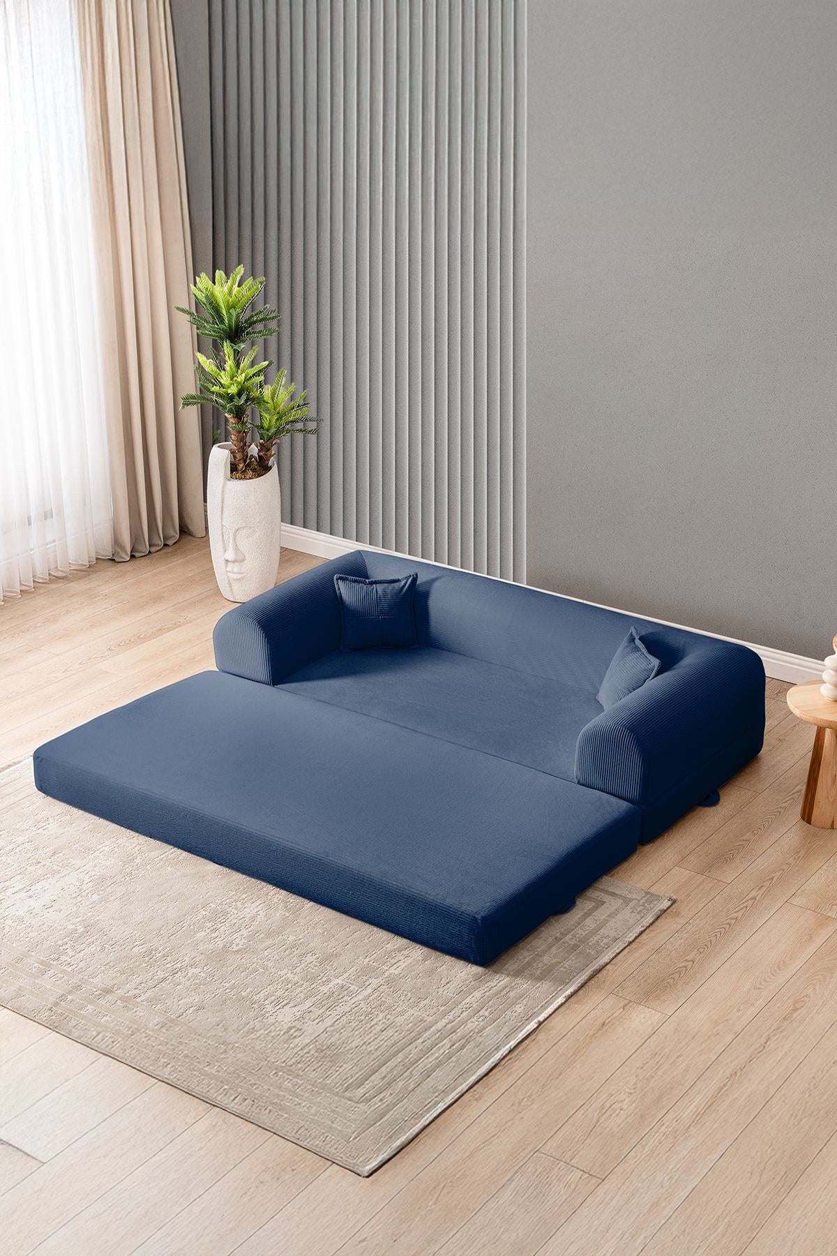 Marineblaues 3-Sitzer Schlafsofa Legom Eco von Hanah Home aus geripptem Cord-Plüschstoff mit zwei Kissen und niedrigem Rückenteil.
