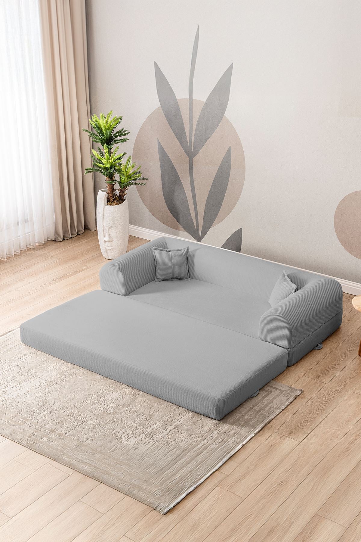 Hellgraues 3-Sitzer Schlafsofa aus geripptem Cord-Plüschstoff mit zwei Kissen, Rollpack-Design und rutschfester Sohle.