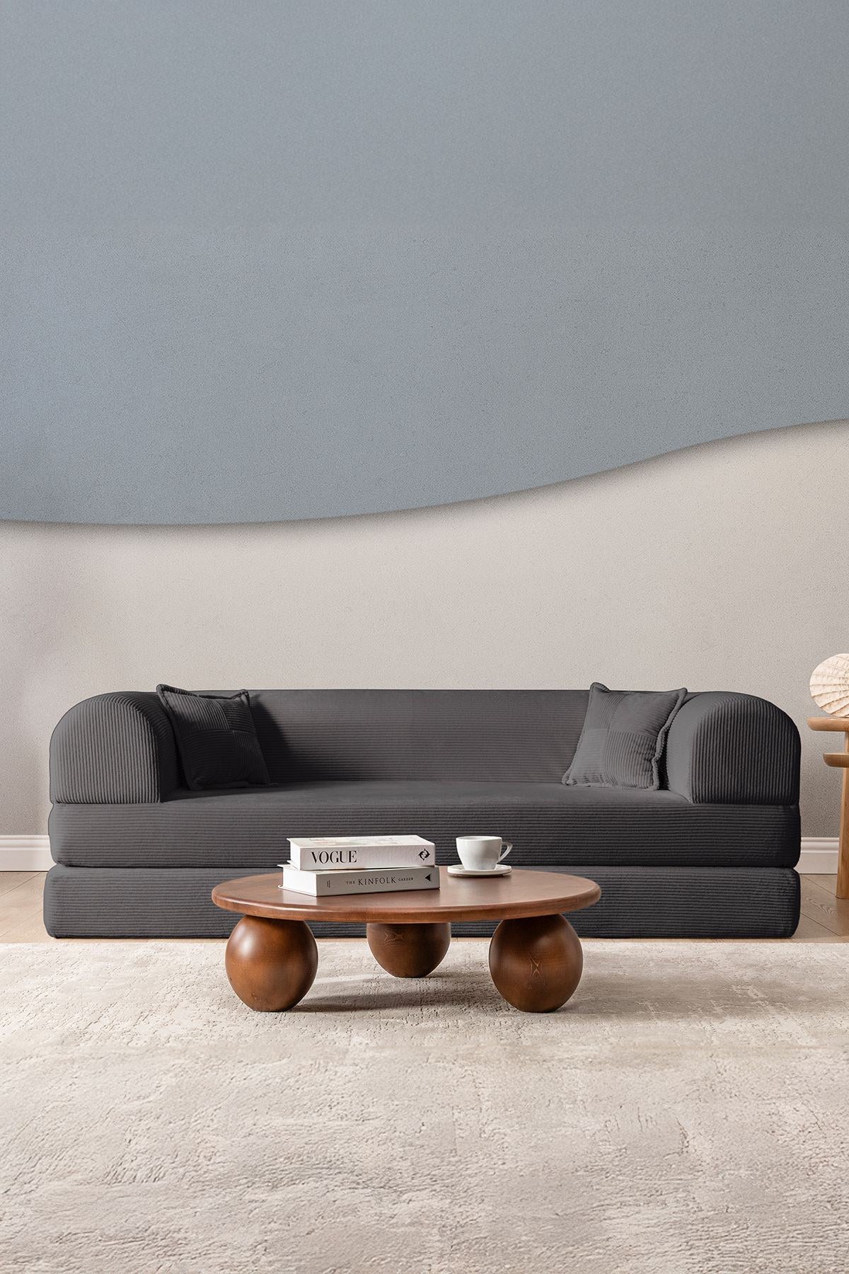 Anthrazitfarbenes 3-Sitzer Schlafsofa aus geripptem Cord-Plüschstoff mit zwei Kissen und sichtbarer rutschfester Sohle.