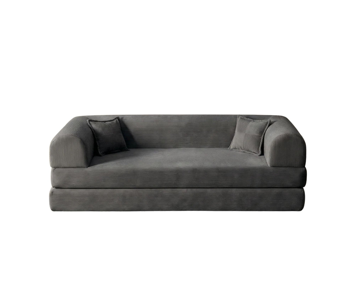 Anthrazitfarbenes 3-Sitzer Schlafsofa aus geripptem Cord-Plüschstoff mit zwei Kissen und sichtbarer rutschfester Sohle.