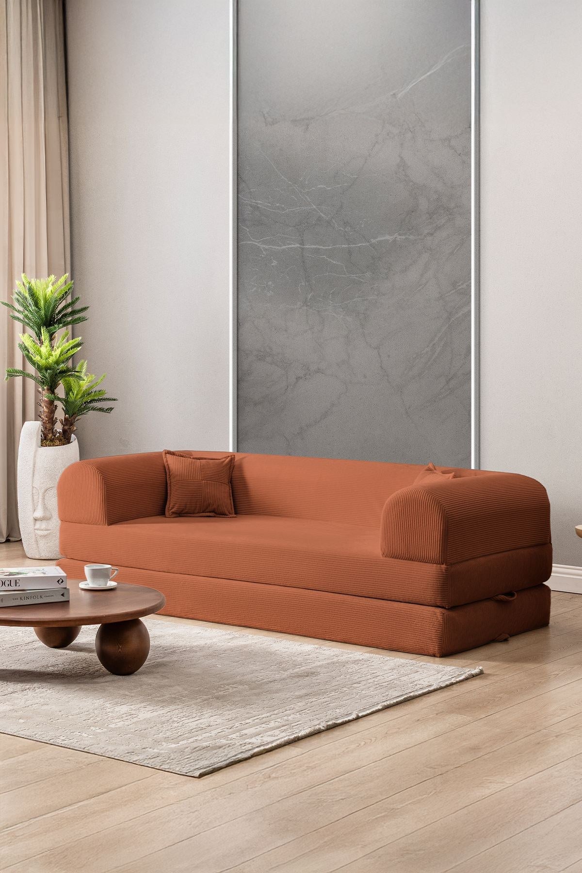Orangefarbenes 3-Sitzer Schlafsofa aus geripptem Plüschstoff mit zwei Kissen, Rollpack-Design und rutschfester Sohle, Frontalansicht.