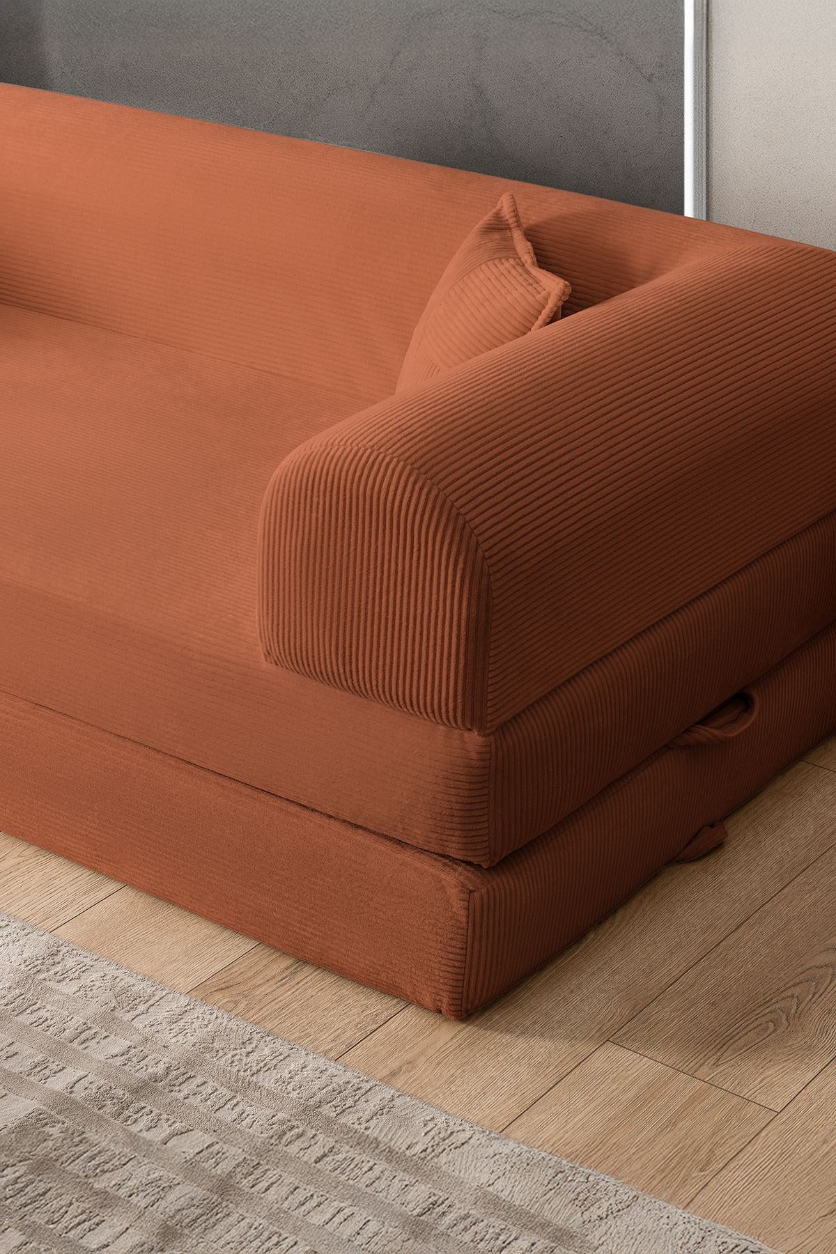 Orangefarbenes 3-Sitzer Schlafsofa aus geripptem Plüschstoff mit zwei Kissen, Rollpack-Design und rutschfester Sohle, Frontalansicht.