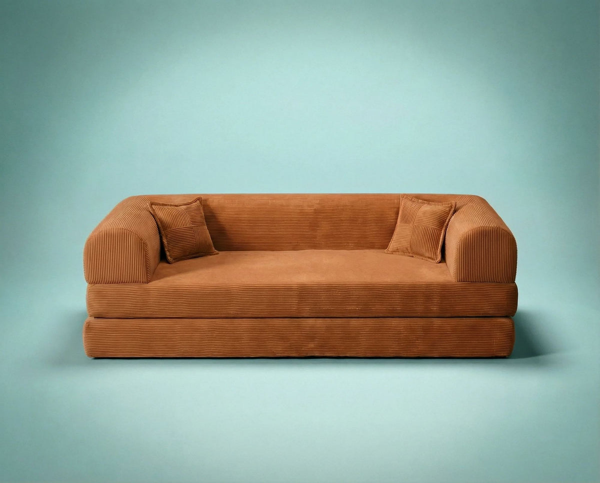 Orangefarbenes 3-Sitzer Schlafsofa aus geripptem Plüschstoff mit zwei Kissen, Rollpack-Design und rutschfester Sohle, Frontalansicht.