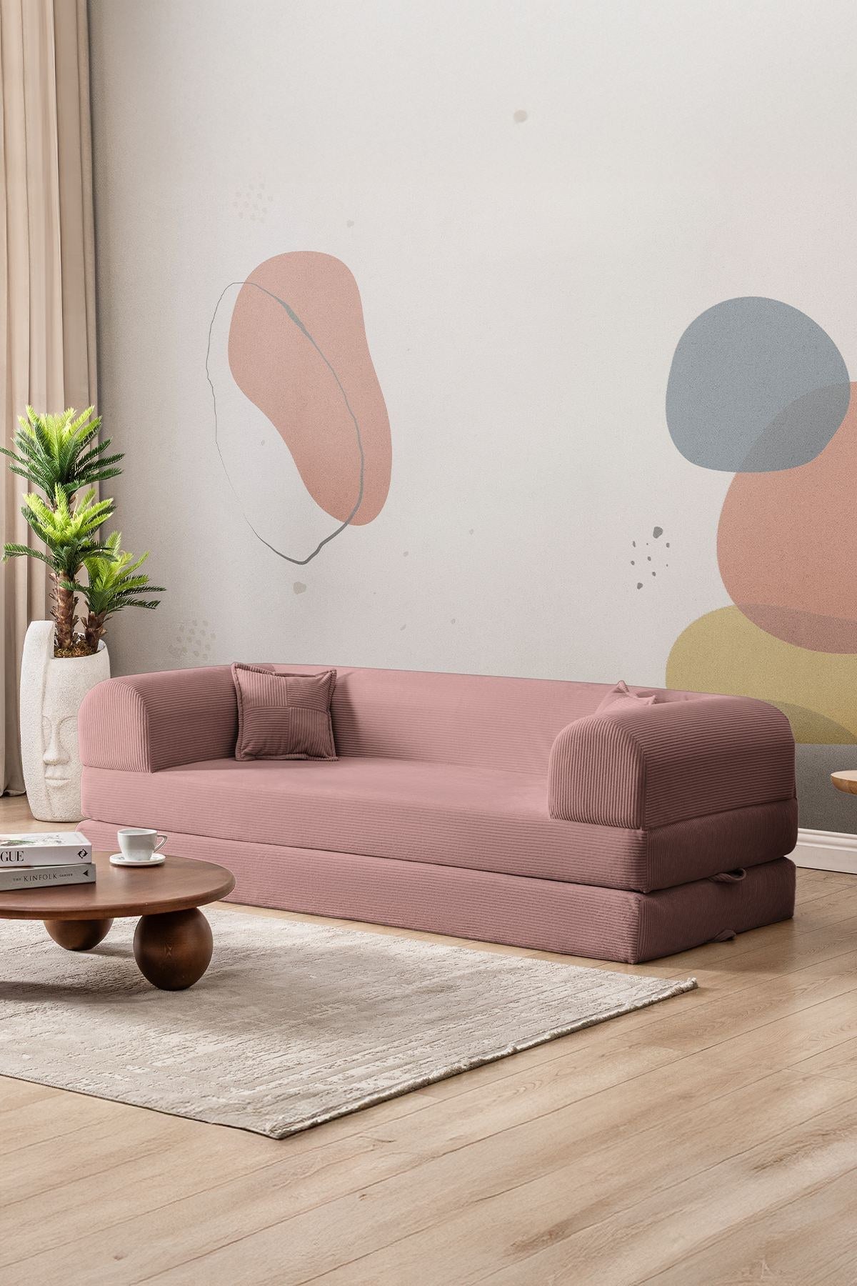 Rosafarbenes 3-Sitzer Schlafsofa aus geripptem Cord-Plüschstoff mit zwei Kissen und rutschfester Sohle, Frontalansicht auf hellem Hintergrund.
