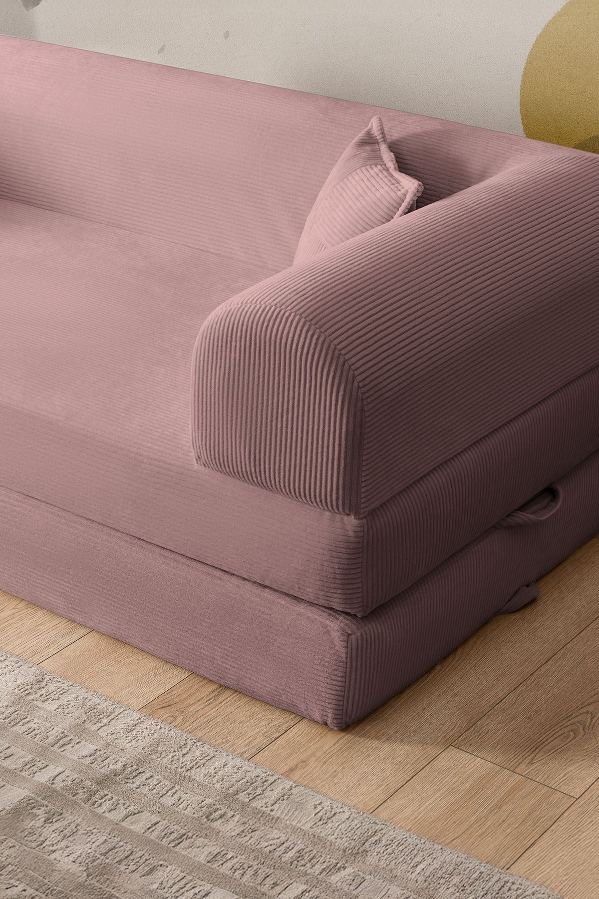 Rosafarbenes 3-Sitzer Schlafsofa aus geripptem Cord-Plüschstoff mit zwei Kissen und rutschfester Sohle, Frontalansicht auf hellem Hintergrund.