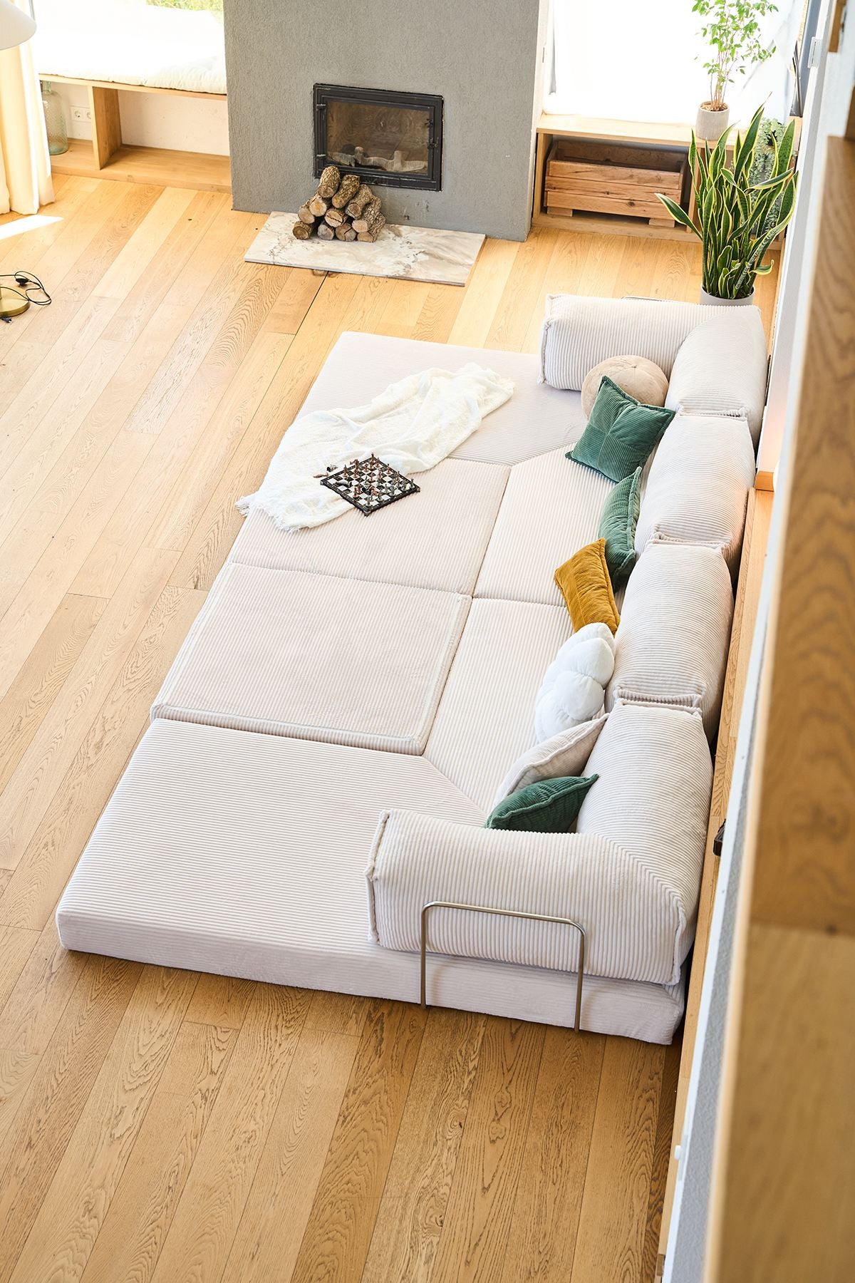 Cremefarbenes Eck-Schlafsofa aus Cord-Plüschstoff mit vier Kissen, rutschfester Sohle und abnehmbarem Bezug, Frontalansicht auf hellem Untergrund.