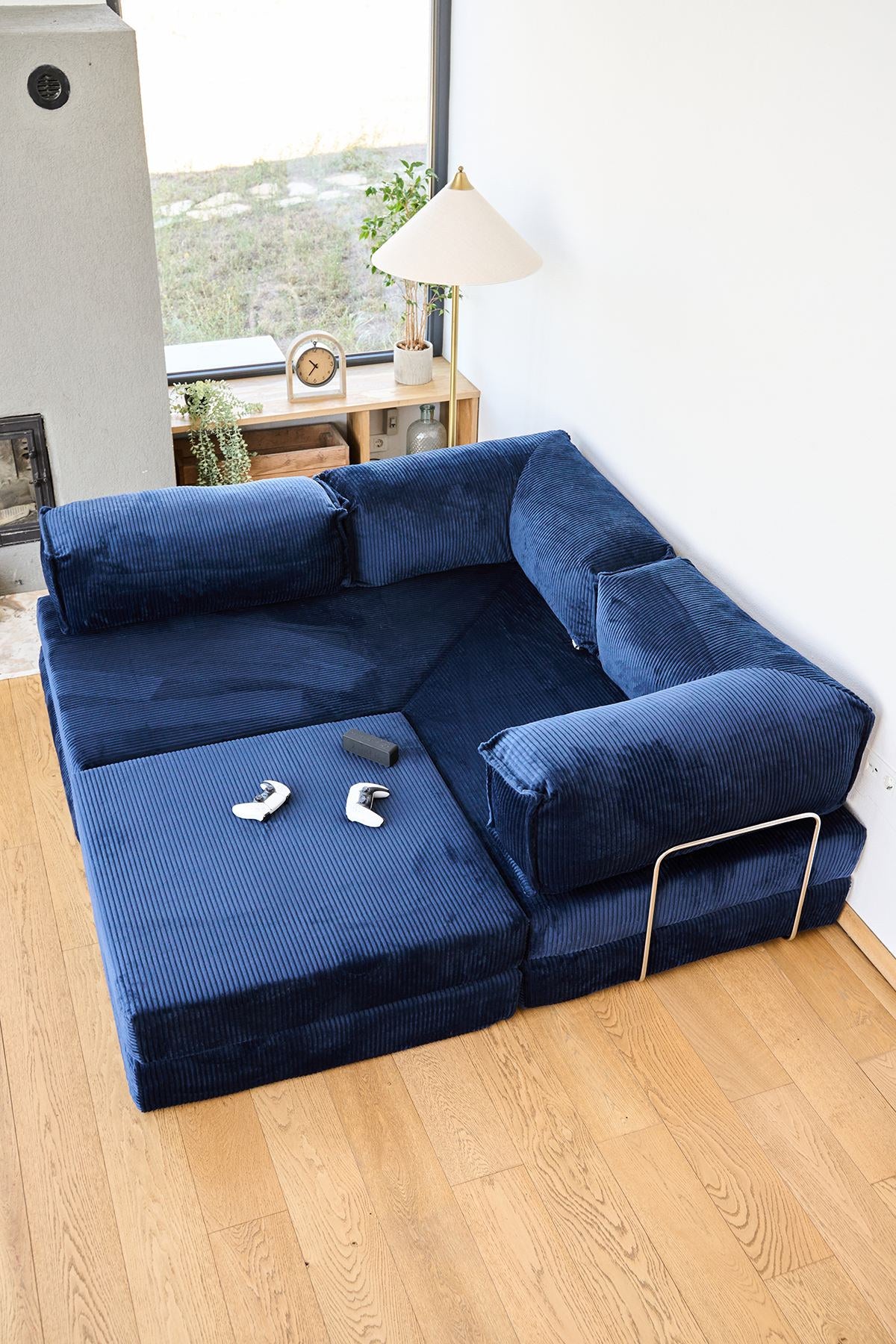 Marineblaues Eck-Schlafsofa aus Cord-Plüschstoff mit vier Kissen, Rollpack-Verpackung und abnehmbarem, waschbarem Bezug.