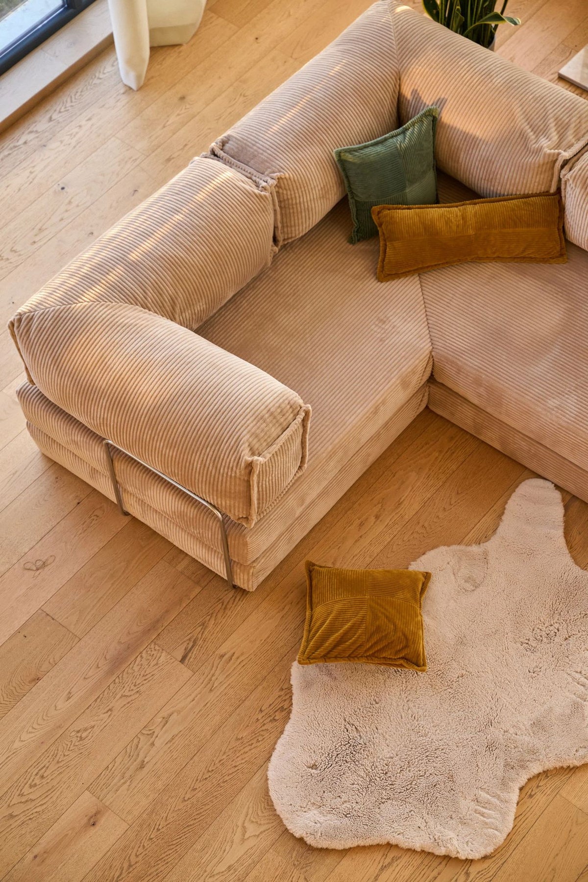 Beiges Eck-Schlafsofa Kanyon von Hanah Home aus geripptem Cord-Plüschstoff, L-Form mit vier Kissen, auf hellem Untergrund fotografiert.