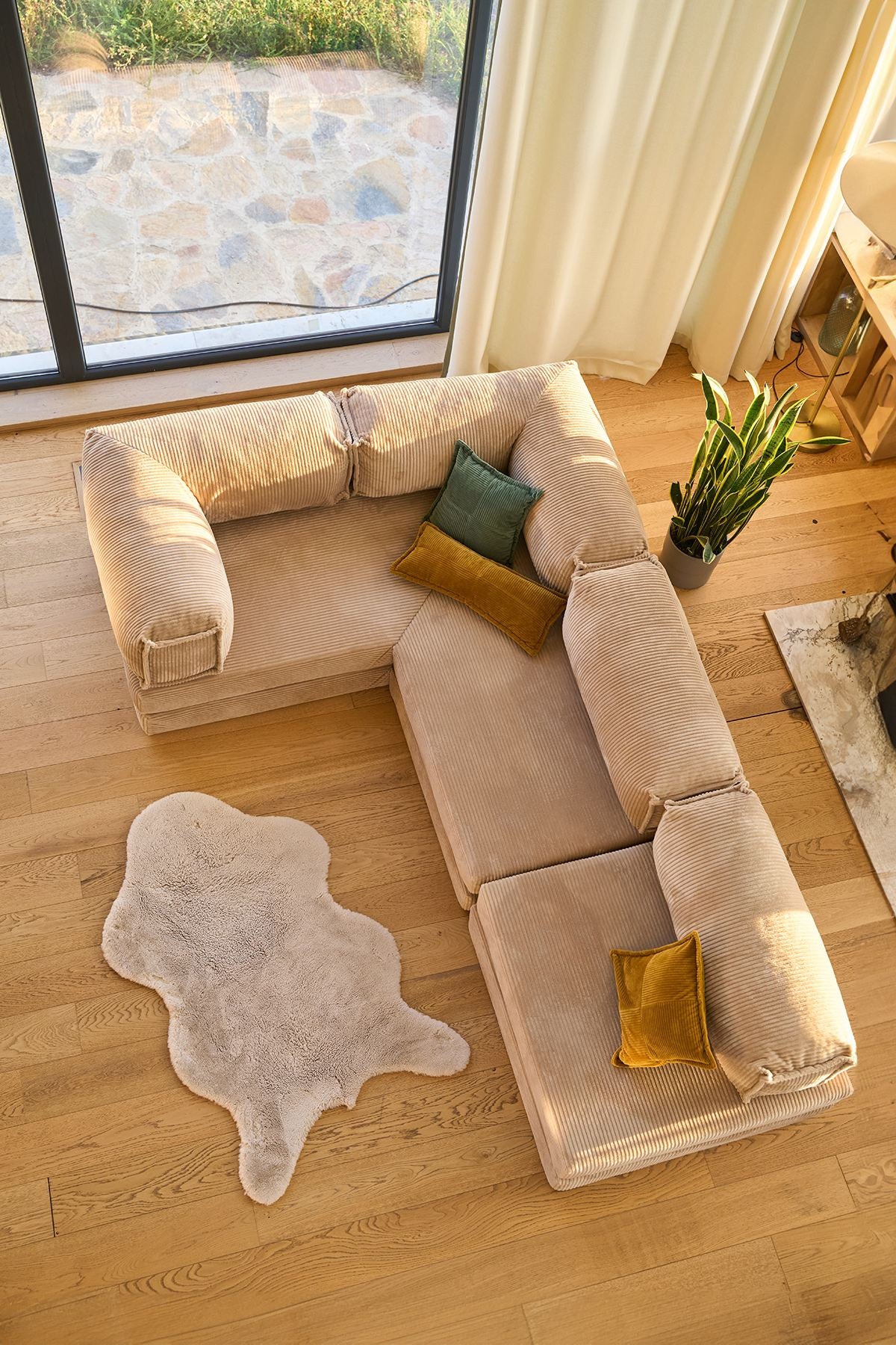 Beiges Eck-Schlafsofa Kanyon von Hanah Home aus geripptem Cord-Plüschstoff, L-Form mit vier Kissen, auf hellem Untergrund fotografiert.