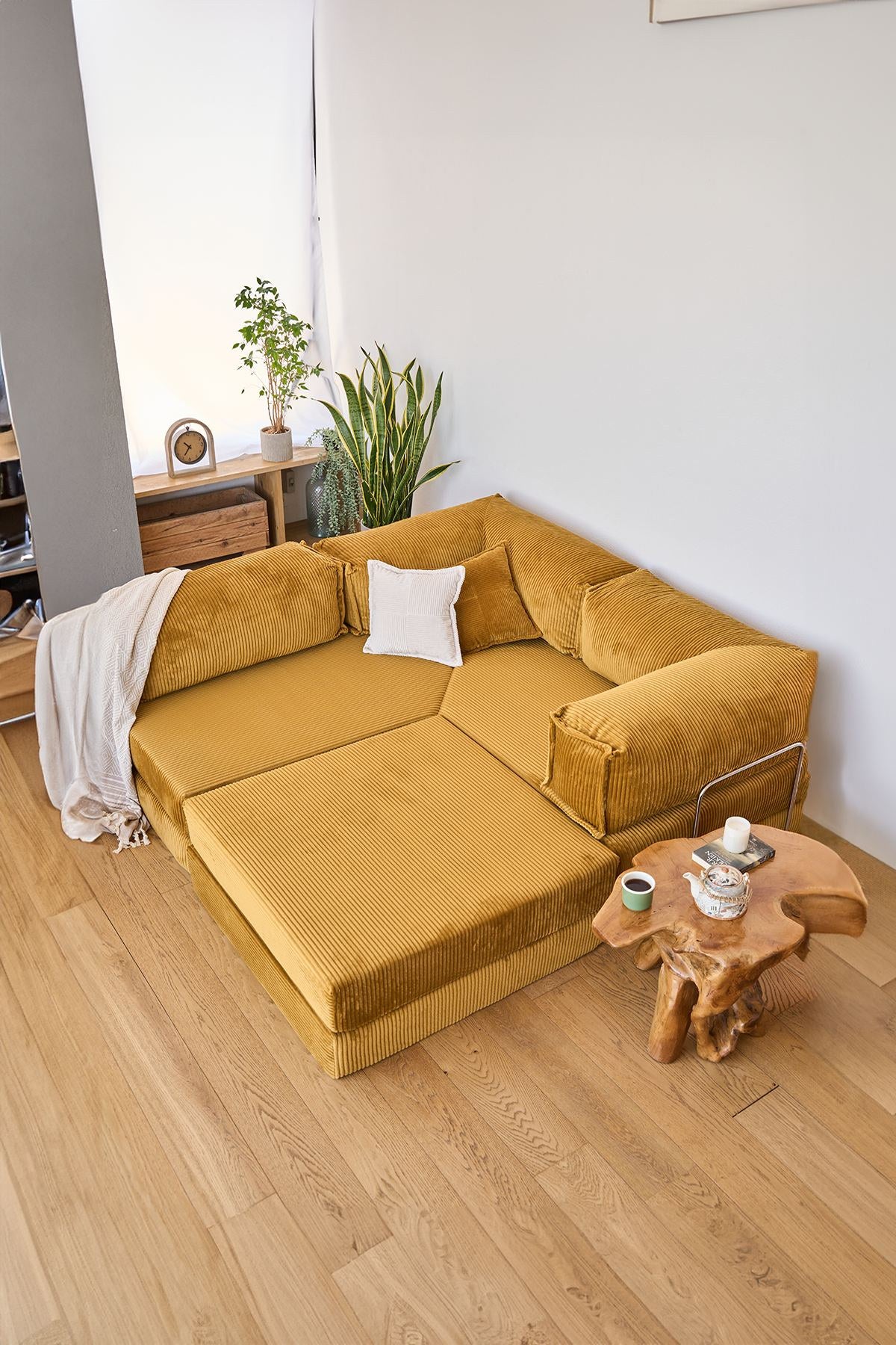 Senfgelbes Eck-Schlafsofa Kanyon von Hanah Home aus geripptem Cord-Plüschstoff mit vier Kissen und rutschfester Sohle.