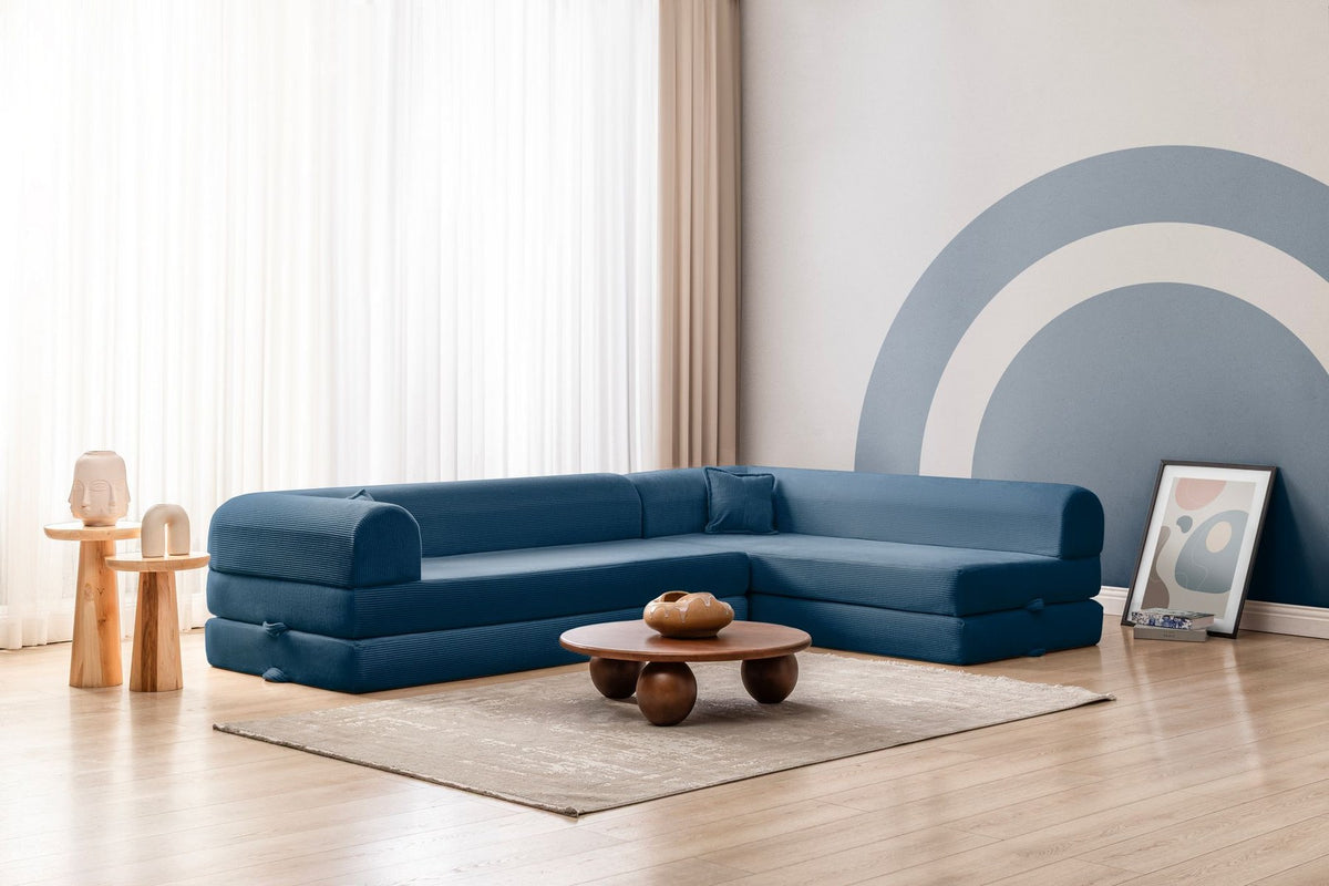 Blaues Ecksofa-Bett aus geripptem Cord-Plüschstoff mit vier Kissen, abnehmbarem Bezug und rutschfester Sohle, Frontalansicht.