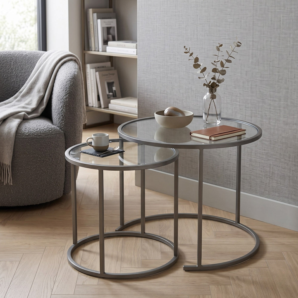 Zwei graue Couchtische aus gehärtetem Glas mit schlankem Metallgestell, unterschiedliche Grössen, nordisches Design, freistehend fotografiert.