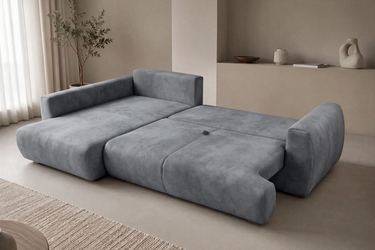 Graues Ecksofa Arthur mit Schlaffunktion, Gestell aus Buchenholz und Spanplatte, Bezug aus Polyester, Kunststoffbeine, zwei Kissen sichtbar.