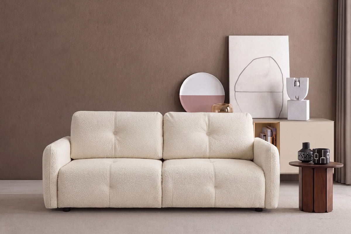 Ecrufarbenes 3-Sitzer Schlafsofa Magic von Hanah Home mit Polyesterbezug, Buchenholzgestell und Kunststoffbeinen im Wohnraum.