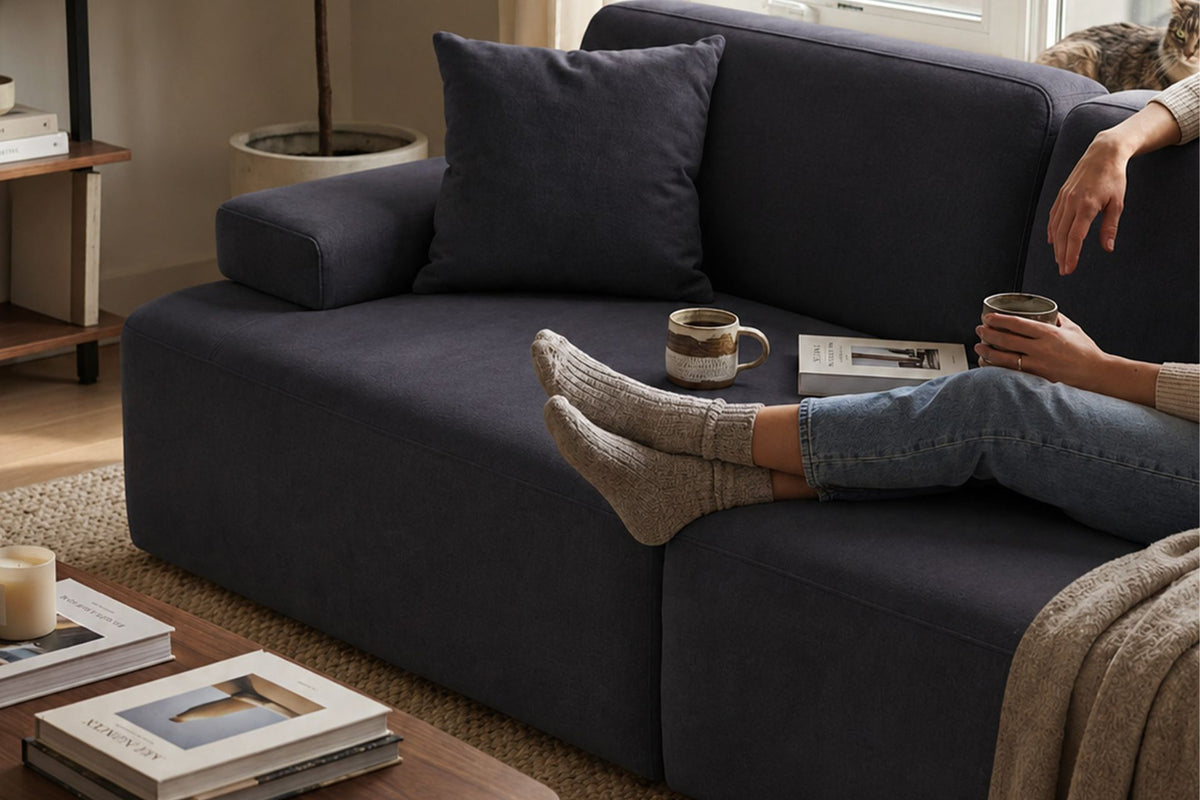Petrolblaues 3-Sitzer Sofa Madlen von Hanah Home mit niedrigen Kunststoffbeinen, Polyesterbezug und zwei Kissen auf hellem Hintergrund.