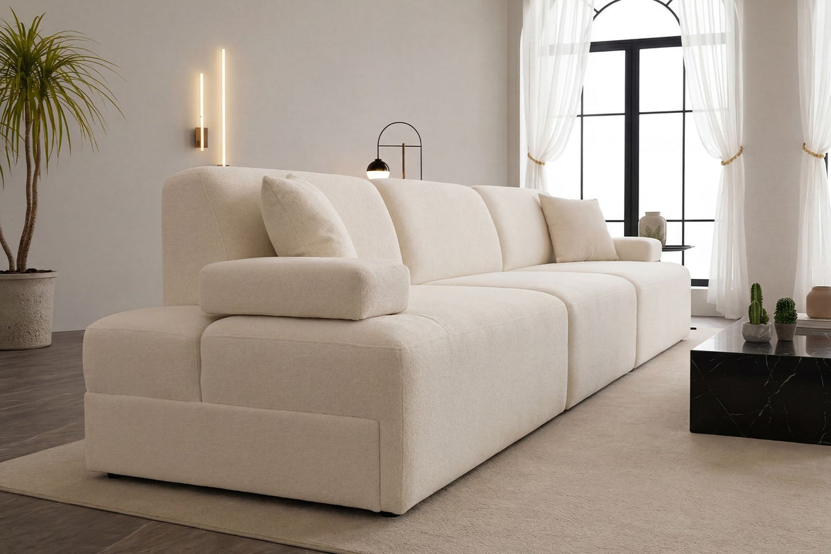 Cremefarbenes Madlen 4-Sitzer Sofa von Hanah Home mit niedrigen Kunststoffbeinen, Polyesterbezug und zwei Kissen auf hellem Untergrund.