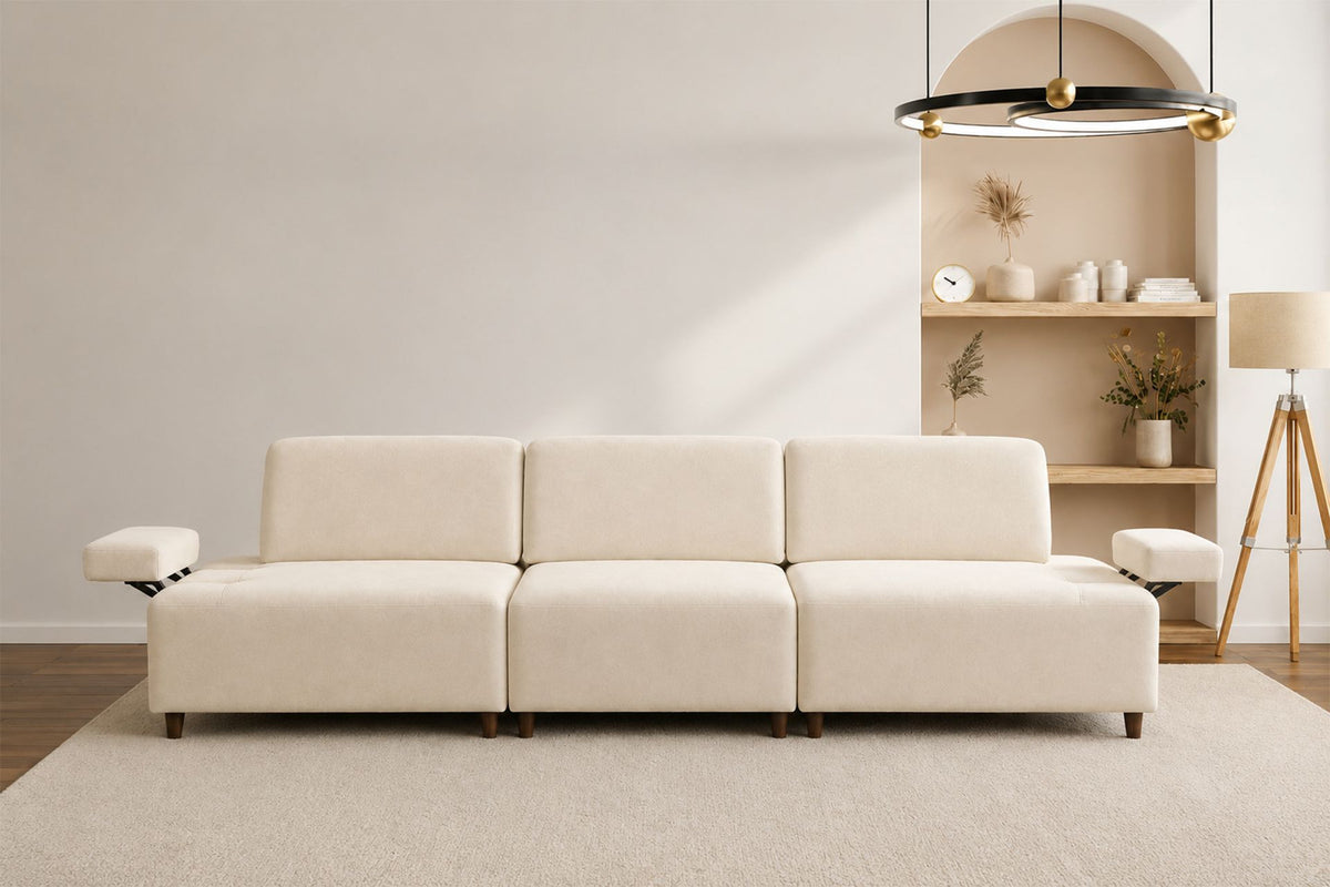 Cremefarbenes 4-Sitzer-Sofa mit hohen Kunststoffbeinen, Polyesterbezug, Buchenholzgestell und zwei losen Kissen auf hellem Hintergrund.