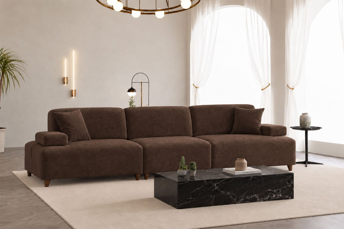 Braunes 4-Sitzer-Sofa Madlen mit hohen Kunststoffbeinen, Polyesterbezug, verstellbarer Rückenlehne und zwei losen Kissen.