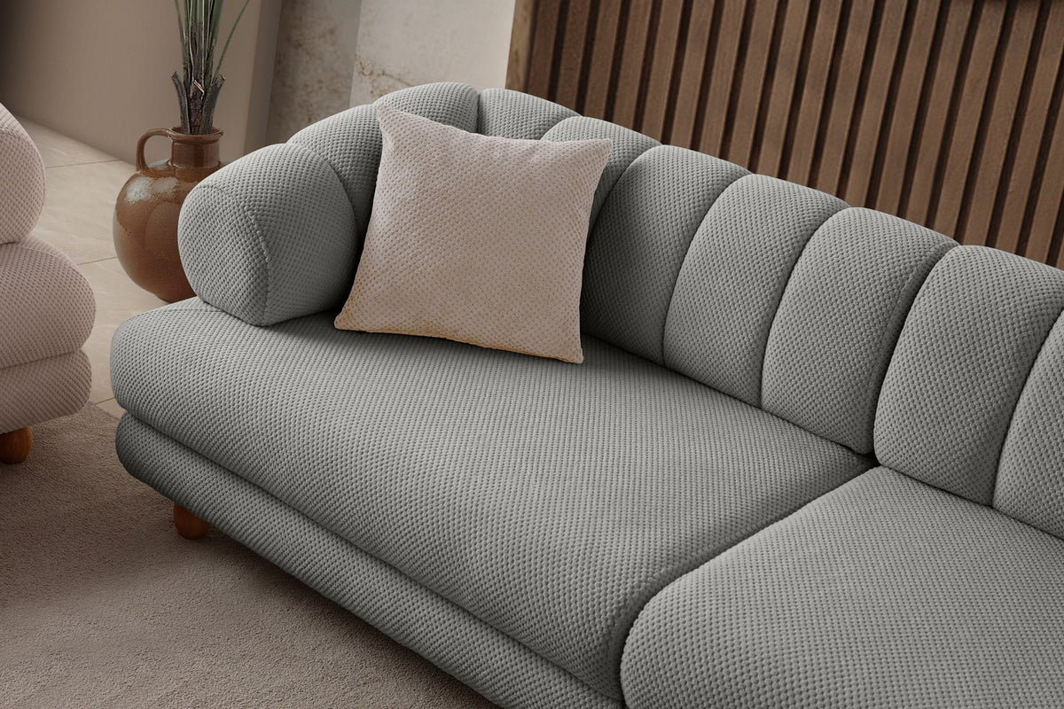 Graues 3-Sitzer Sofa Gloria von Hanah Home mit Polyesterbezug in Tuna-Struktur, Holzbeinen und zwei losen Kissen auf hellem Untergrund.