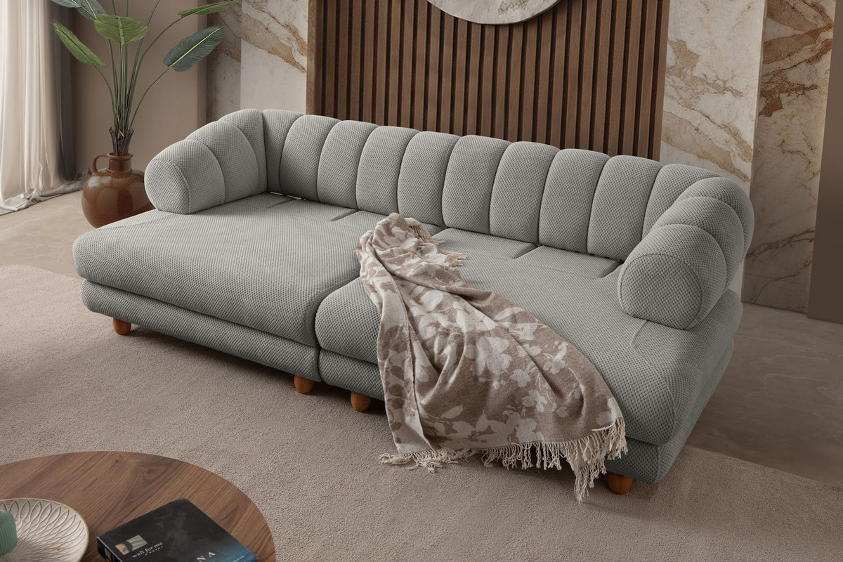 Graues 3-Sitzer Sofa Gloria von Hanah Home mit Polyesterbezug in Tuna-Struktur, Holzbeinen und zwei losen Kissen auf hellem Untergrund.