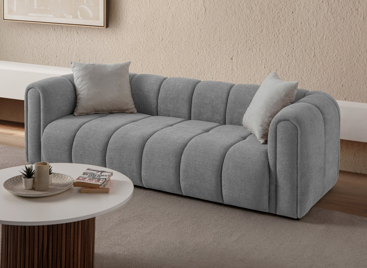 Graues 3-Sitzer Sofa N-Line von Hanah Home mit Boucle-Stoffbezug, Kunststoffbeinen und zwei losen Kissen im Wohnraum.