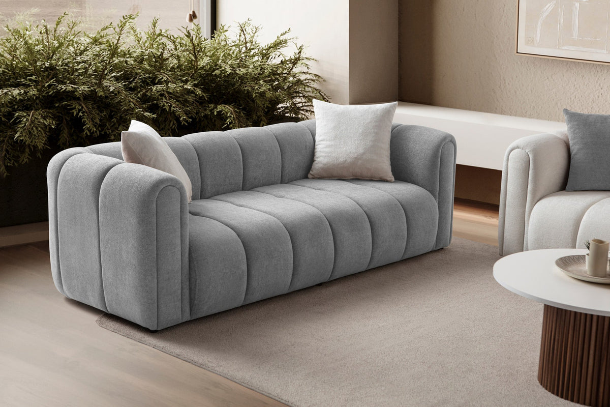 Graues 3-Sitzer Sofa N-Line von Hanah Home mit Boucle-Stoffbezug, Kunststoffbeinen und zwei losen Kissen im Wohnraum.