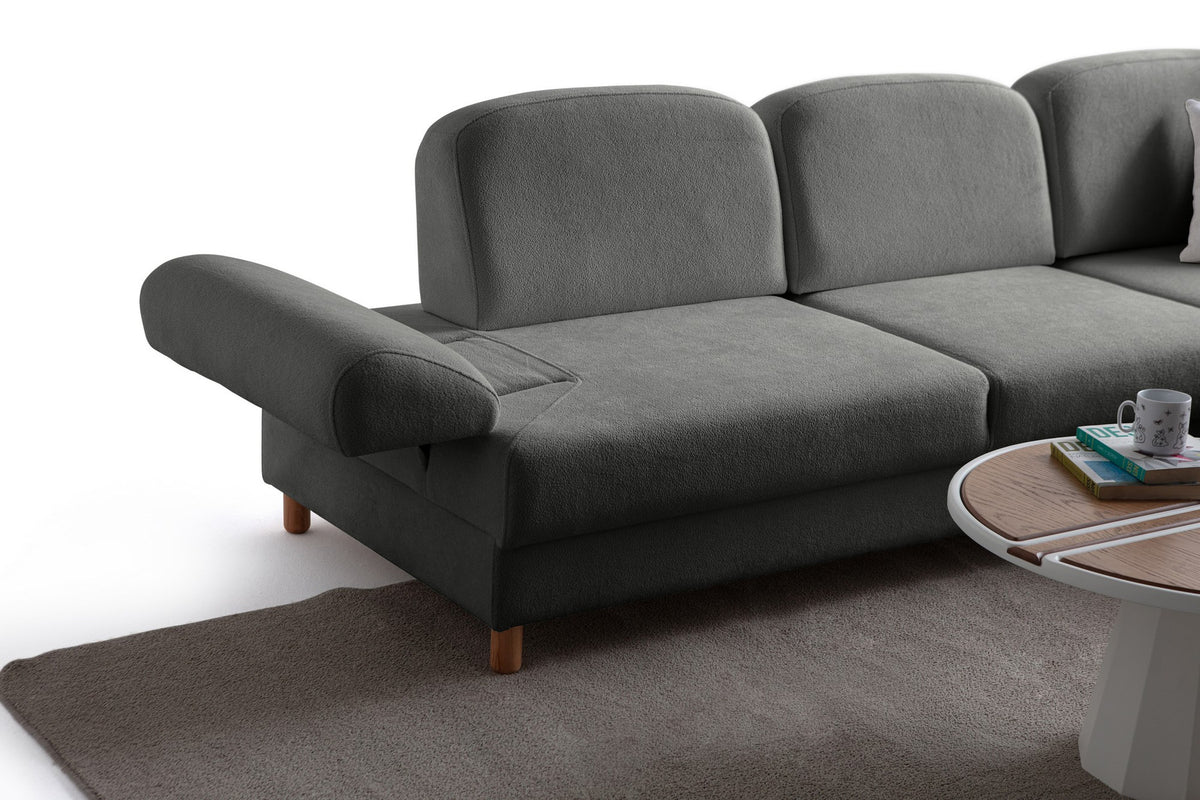 Anthrazitfarbenes Eck-Schlafsofa Aries von Hanah Home mit Coco-Boucle-Bezug, Holzbeinen und ausklappbarer Liegefläche in Wohnraumumgebung.
