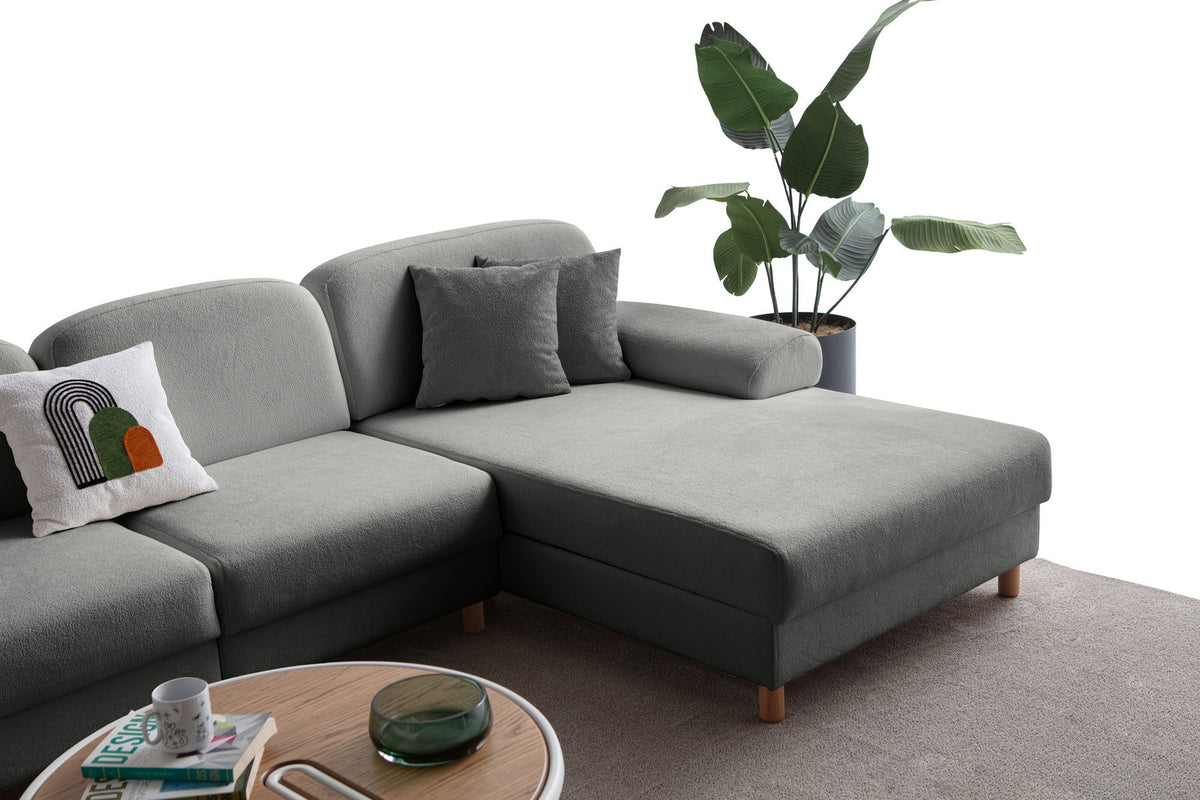 Anthrazitfarbenes Eck-Schlafsofa mit Coco-Boucle-Stoffbezug, Holzbeinen und rechter Truhe, fotografiert freistehend im Raum.