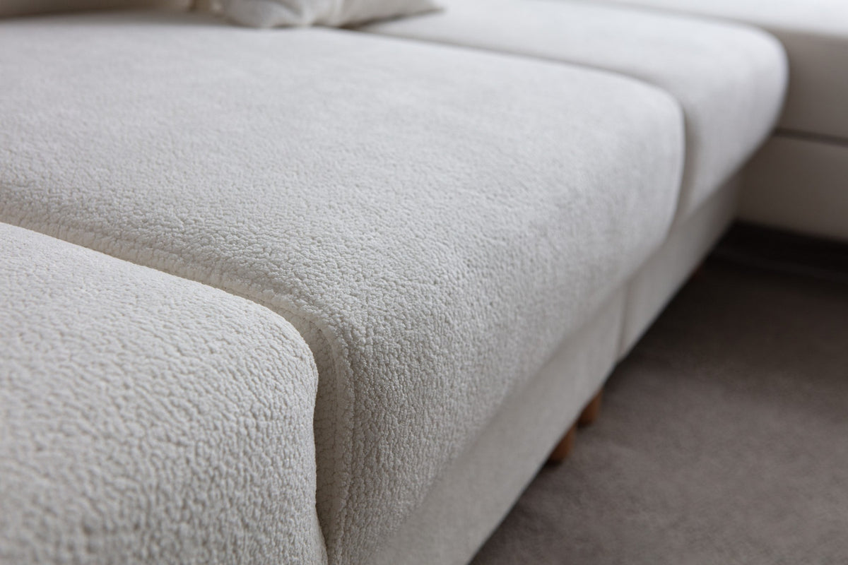 Weisses Eck-Schlafsofa Aries Relax Joker mit Coco-Boucle-Stoff, Holzbeinen und integrierter Aufbewahrungstruhe, rechte Ausführung, Ansicht von vorne.