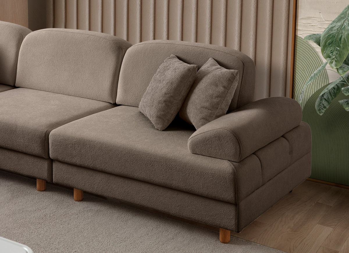 Braunes Eck-Schlafsofa Aries Modular S von Hanah Home mit Coco-Boucle-Stoff, Holzbeinen und vier Kissen in einem Wohnzimmer.